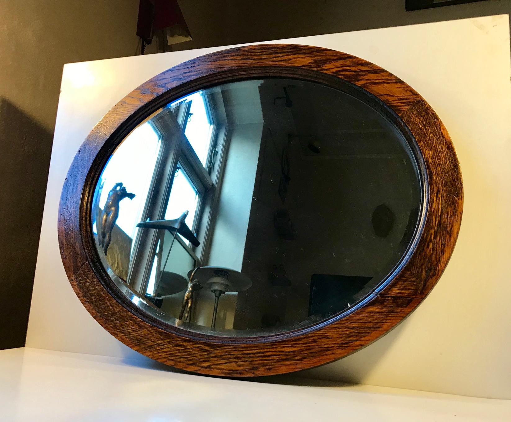 Beveled wall mirror with solid cross-cut oak frame. Made by an English furniture maker, circa 1920-1925. It has cork implements to the backside that allows it to hang straight/leveled on the wall.