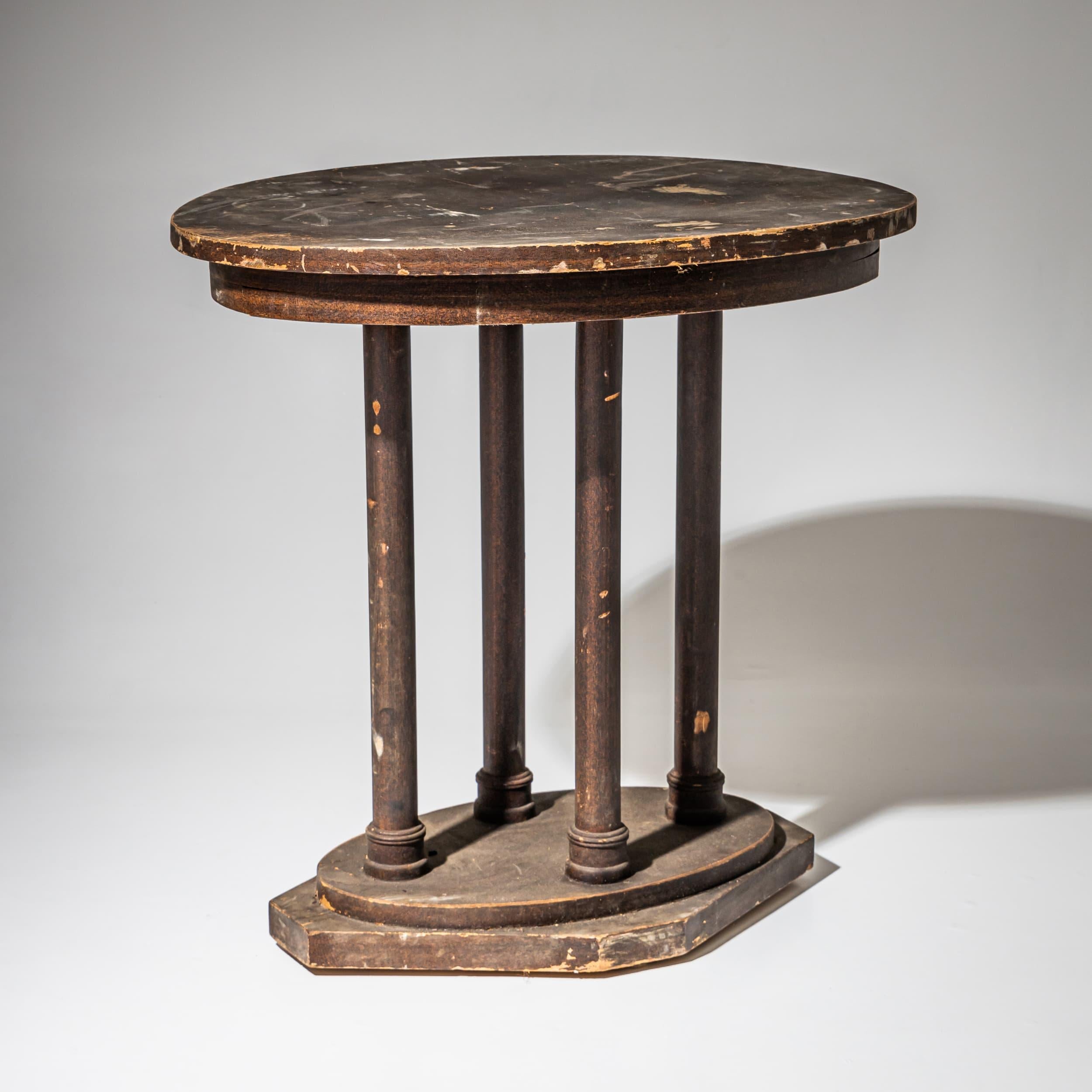 Oval table in the style of Art Nouveau / Viennese Secession with four cylindrical legs resting on a rhomboid base with an oval platform. The surface has a brown patina. The table remains in its unrestored original condition, showing age-related wear