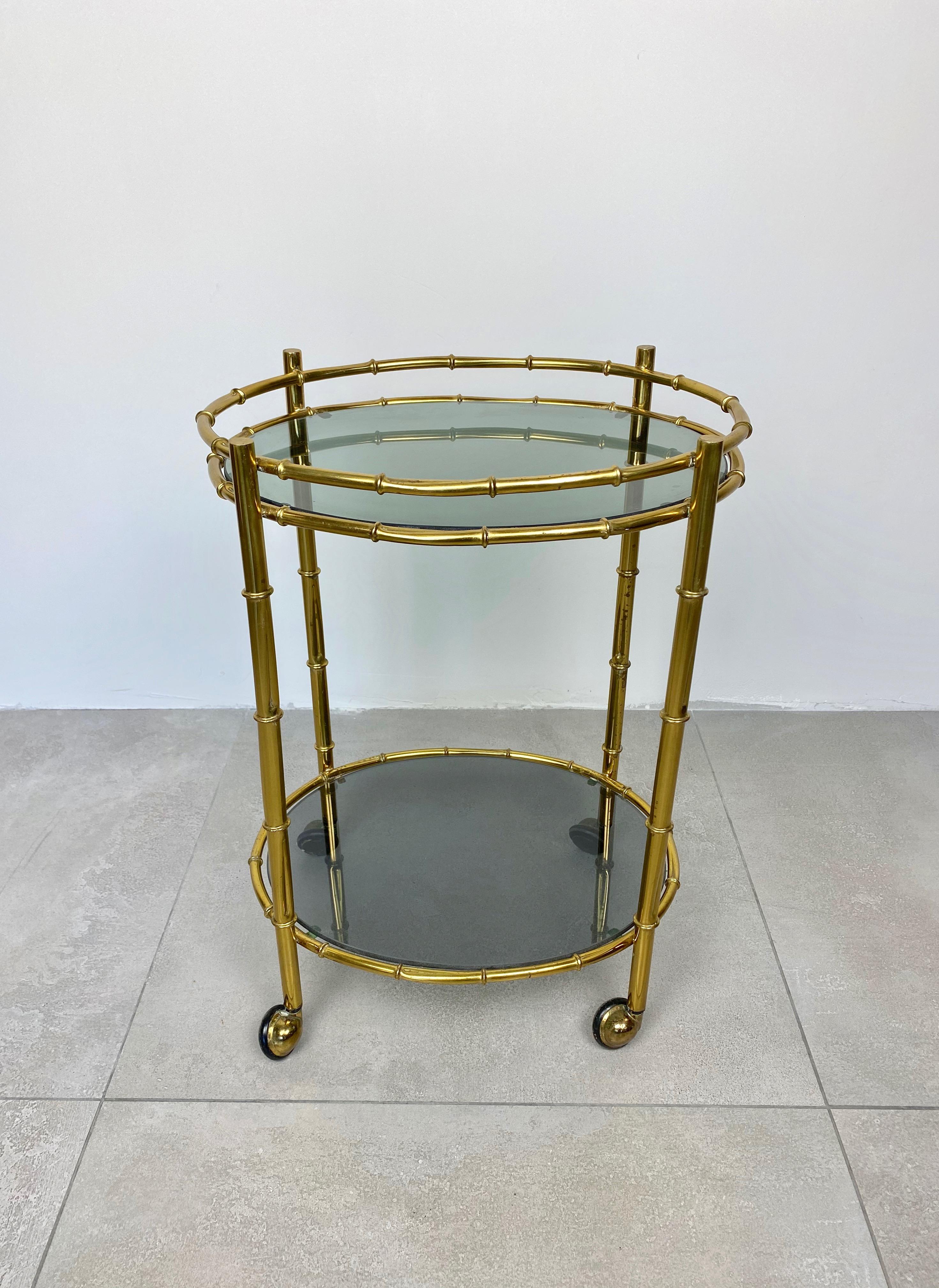 Bar cart with two oval shelves in a brass and smoked glass structure, Italy, 1960s.