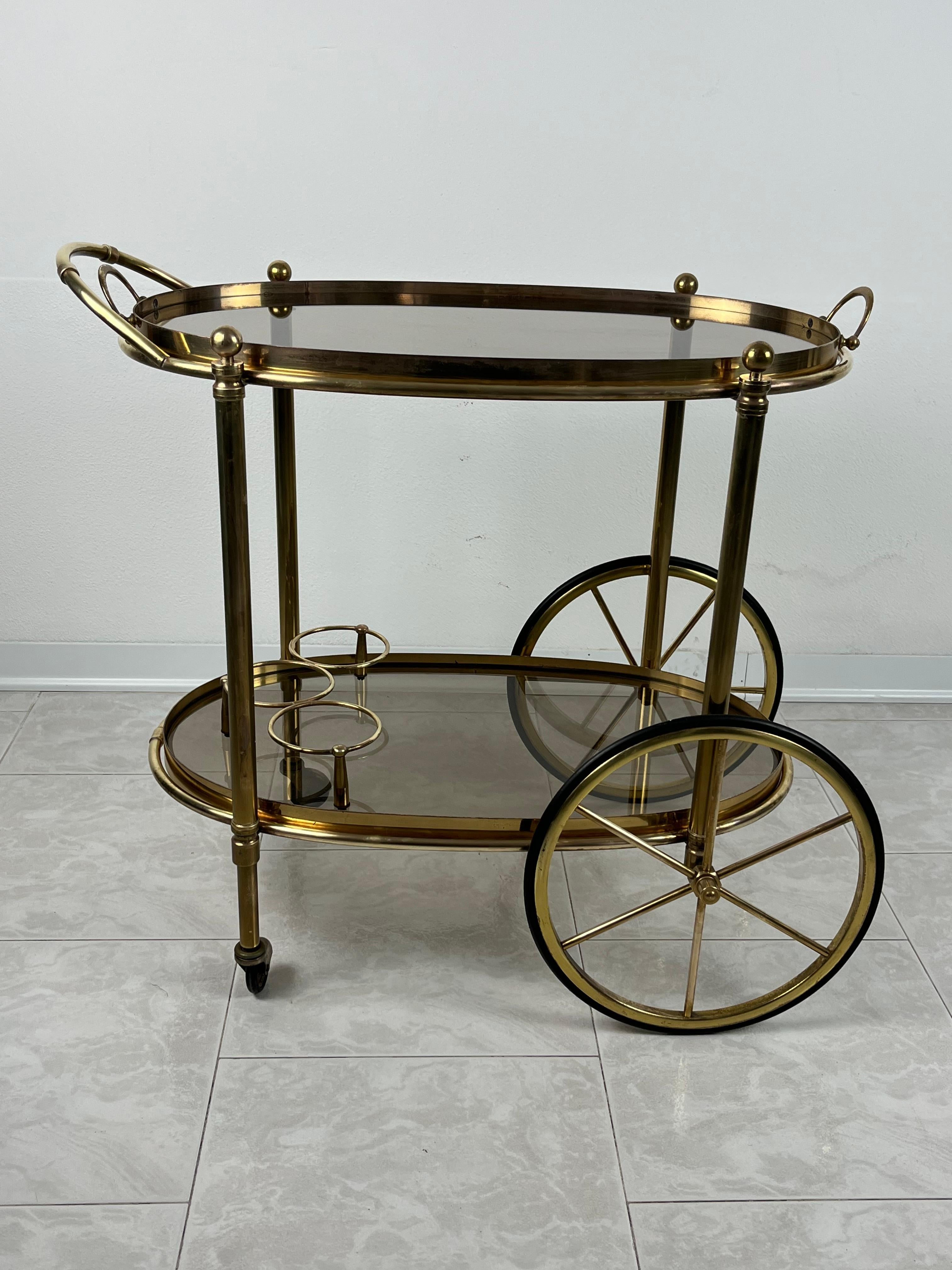 Oval Brass Bar Trolley  with Smoked Glass, Made in Italy, 1960s.
It has always belonged to my family and was bought by my great-grandfather.
The brass shows normal signs of ageing. The peculiarity of this trolley is that the upper part becomes a