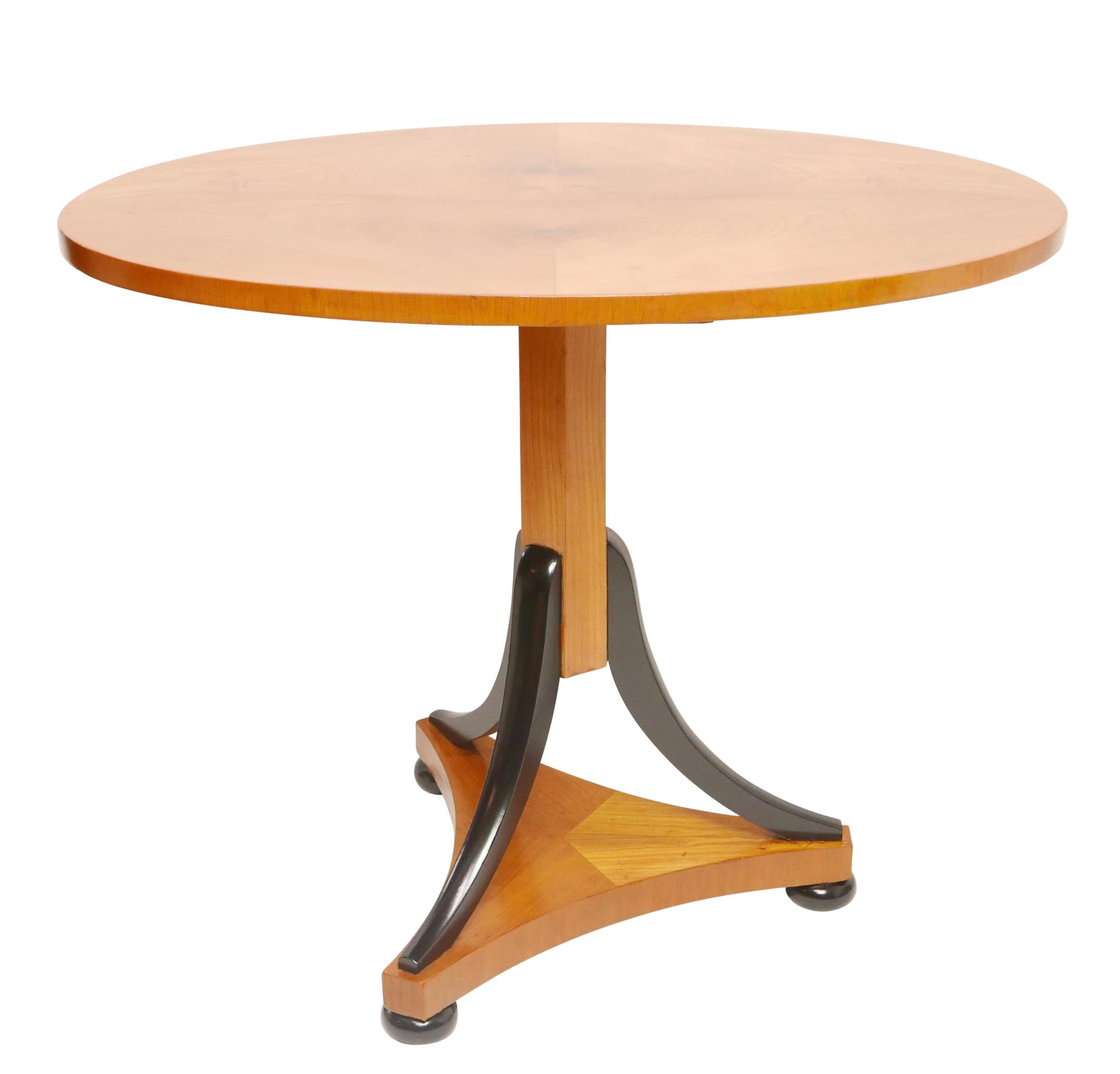 Ungewöhnlicher ovaler Kirschholztisch im Biedermeier-Stil mit kippbarer Tischplatte, gestützt auf eine Mittelsäule mit drei gespreizten ebonisierten Stützen, die an einem dreiteiligen Sockel befestigt sind und auf ebonisierten Stollenfüßen