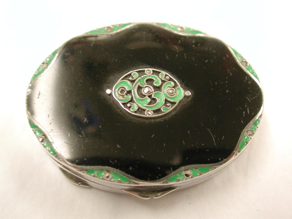 Boîte ovale en argent émaillé noir et vert avec marcassite, Londres, 1930.
Intérieur en argent doré avec moteur tournant en dessous.
 