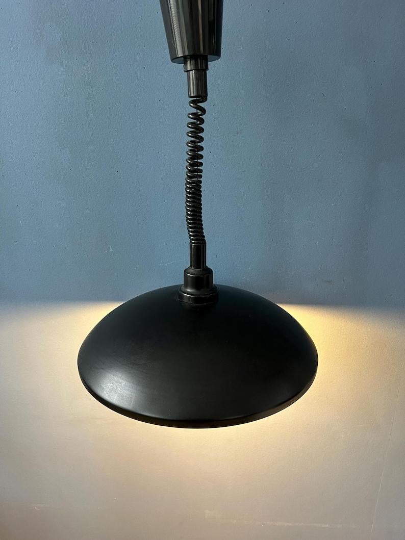 Lampada a sospensione di metà secolo in metallo nero. La lampada è laccata in nero opaco. Può essere facilmente tirato su e giù con il meccanismo di salita e discesa. La lampada è realizzata in metallo e ha un top e un tappo in plastica. La lampada