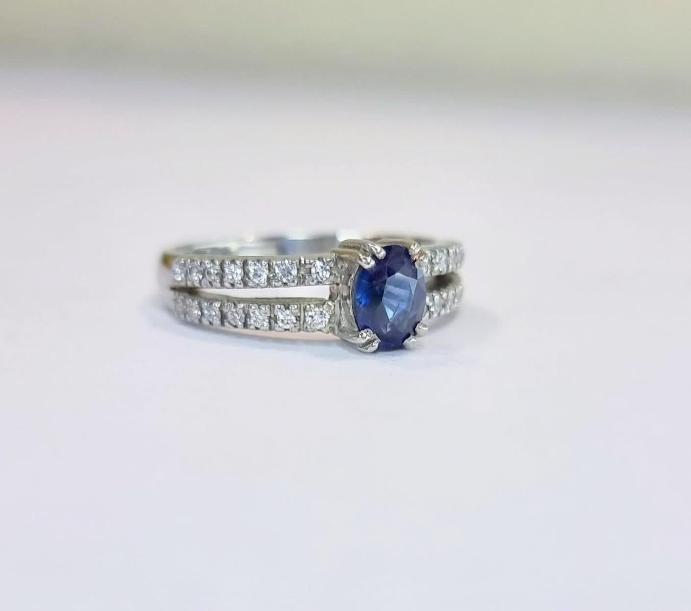Oval Natural Blue Sapphire and Zircon Engagement Ring with Distinctive Double Band

This exquisite 6.8 x 6.6mm ring features a captivating 1ct oval-cut blue sapphire as its radiant centerpiece. The elegant oval shape of the gemstone accentuates its