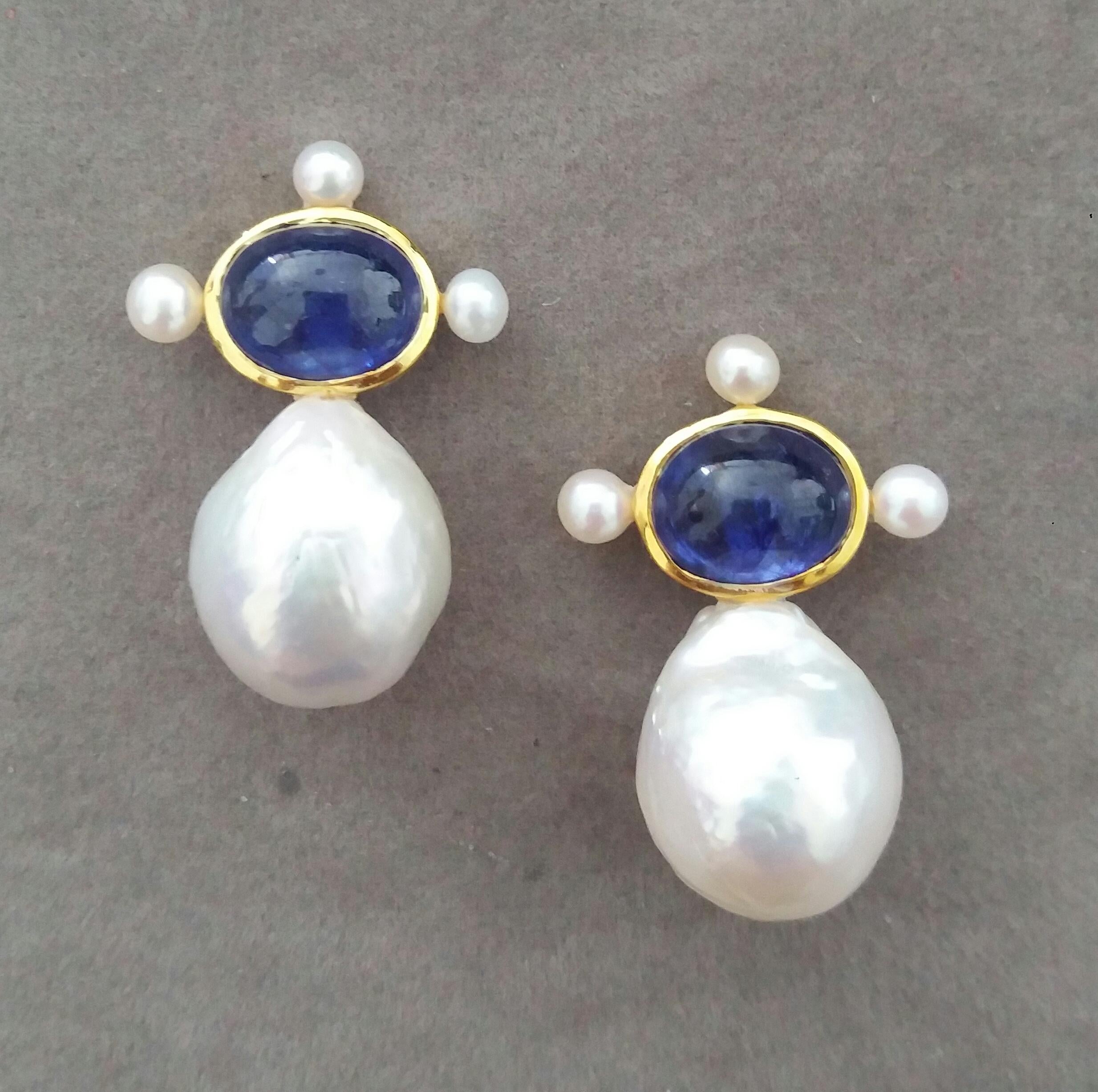 These elegant and handmade earrings have 2 Oval  Blue Sapphire cabs measuring 8 x 10 mm set in a 14 Kt yellow gold bezel with 3 small round pearls of 4mm on 3 sides at the top to which are suspended 2 very good luster White Pear Shape Baroque Pearls