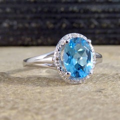 Oval Blue Topaz and Diamond Illusion Halo Cluster Ring in White Gold