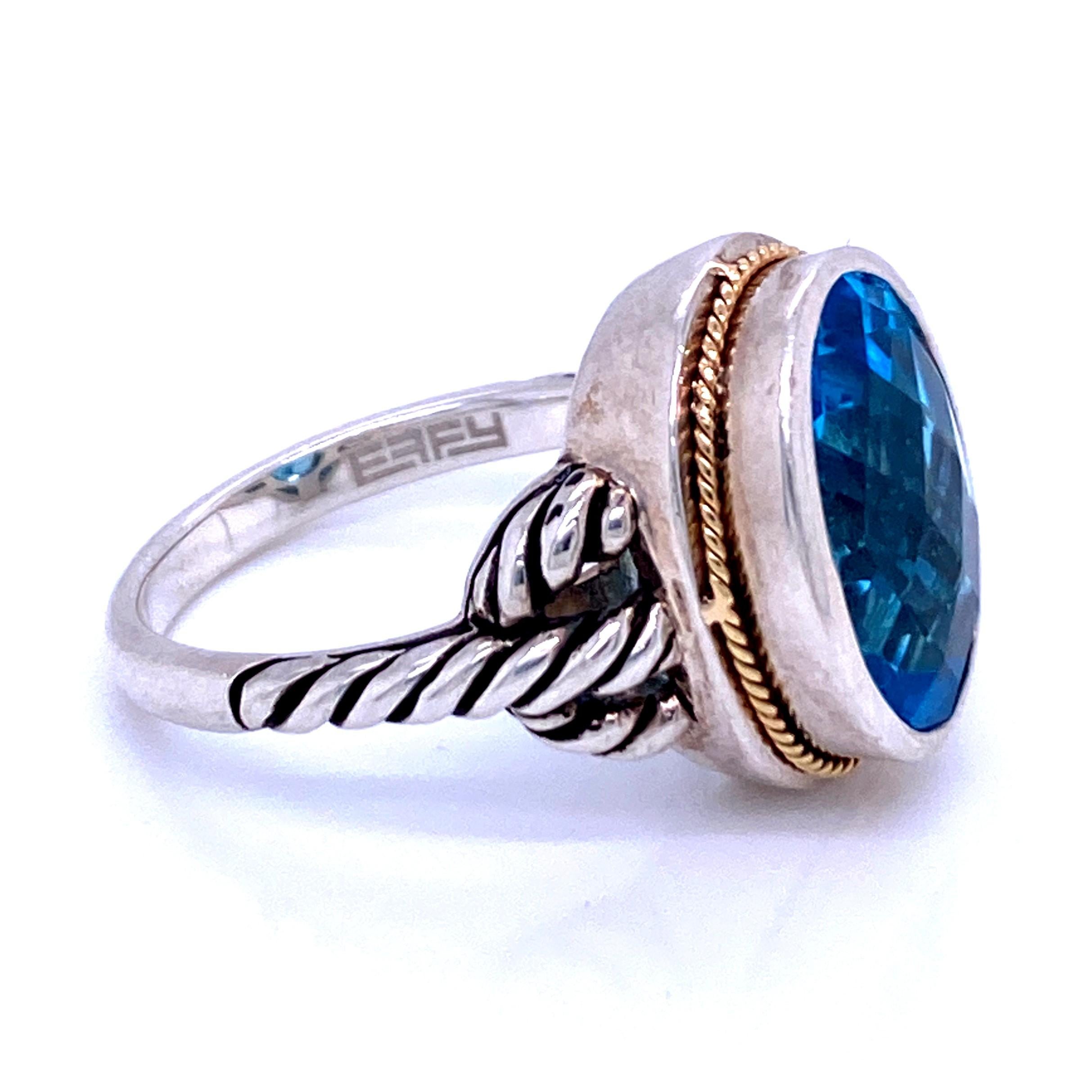 One sterling silver and 18 karat yellow gold (stamped 18K 925 EFFY) ring set with one 14 x 10mm oval blue topaz set in a silver bezel with 18 karat yellow gold edge rope design on the shoulders.  The shank measures 2.2mm near the top of the ring and