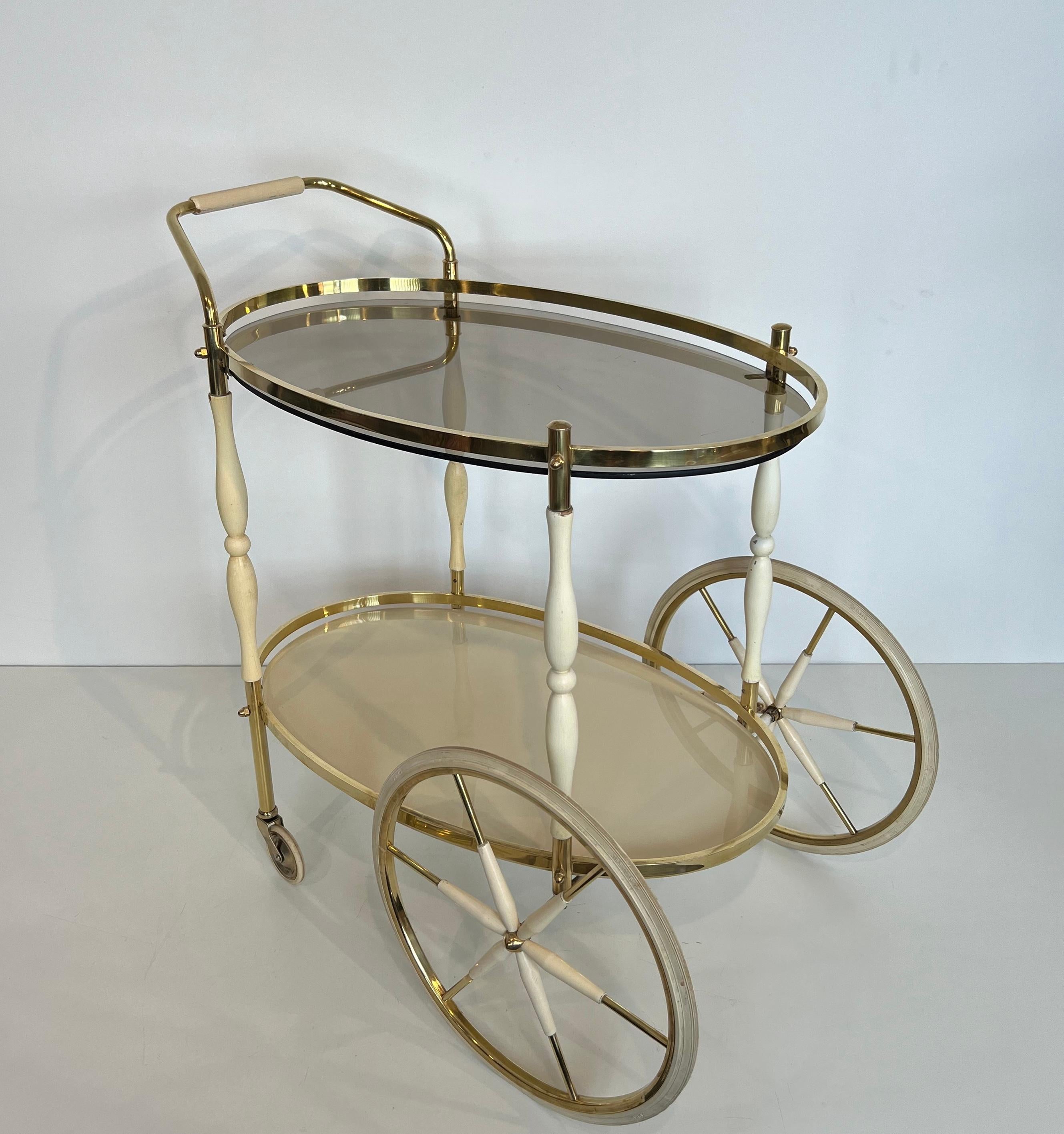 This very nice and elegant design oval bar cart is made of brass and lacquered wood. This is an Italian work. Circa 1940