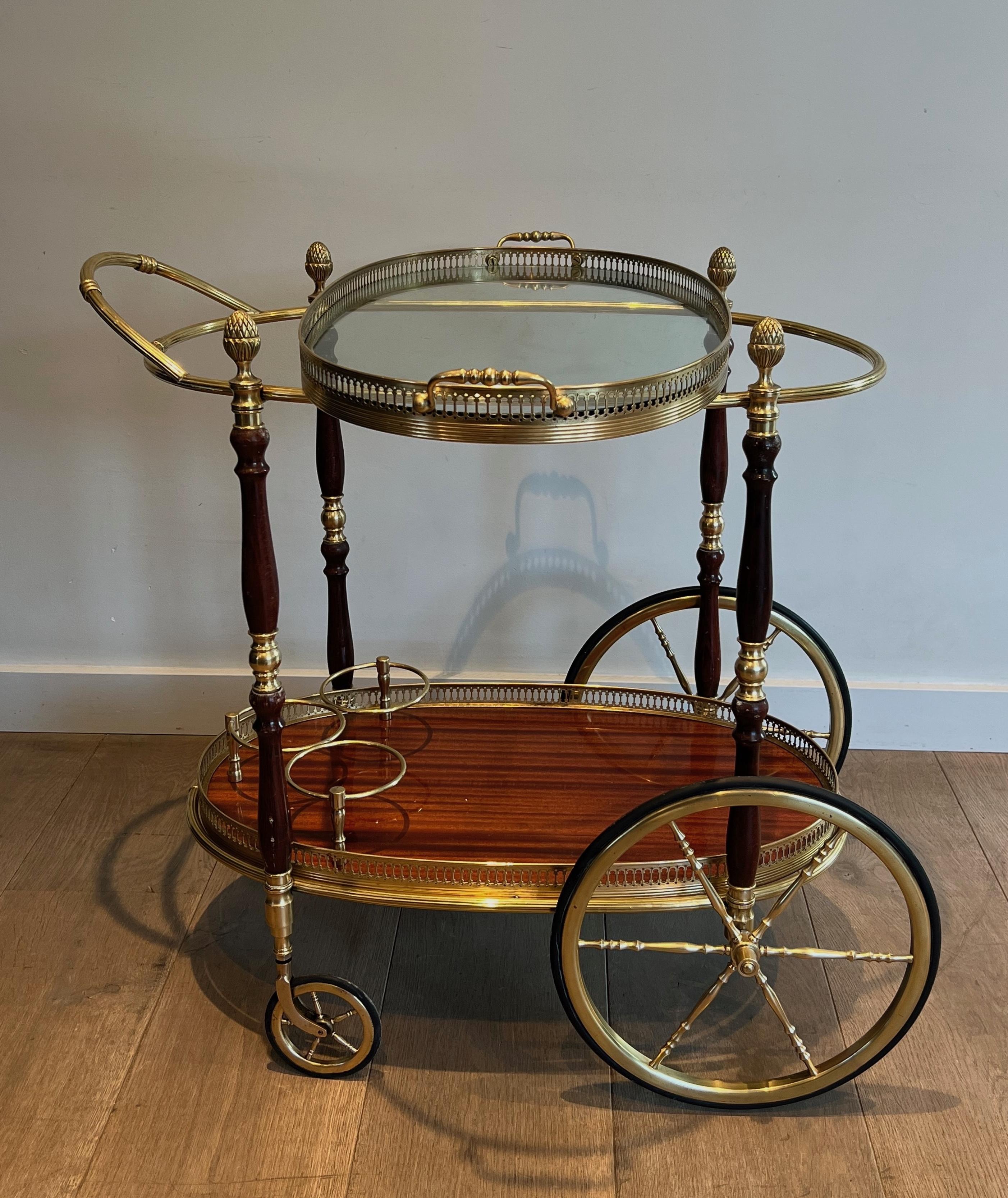 This neoclassical style oval bar cart is made of brass and mahogany with removable trays. This drinks trolley is a French work by famous designer Maison Bagués. Circa 1940
