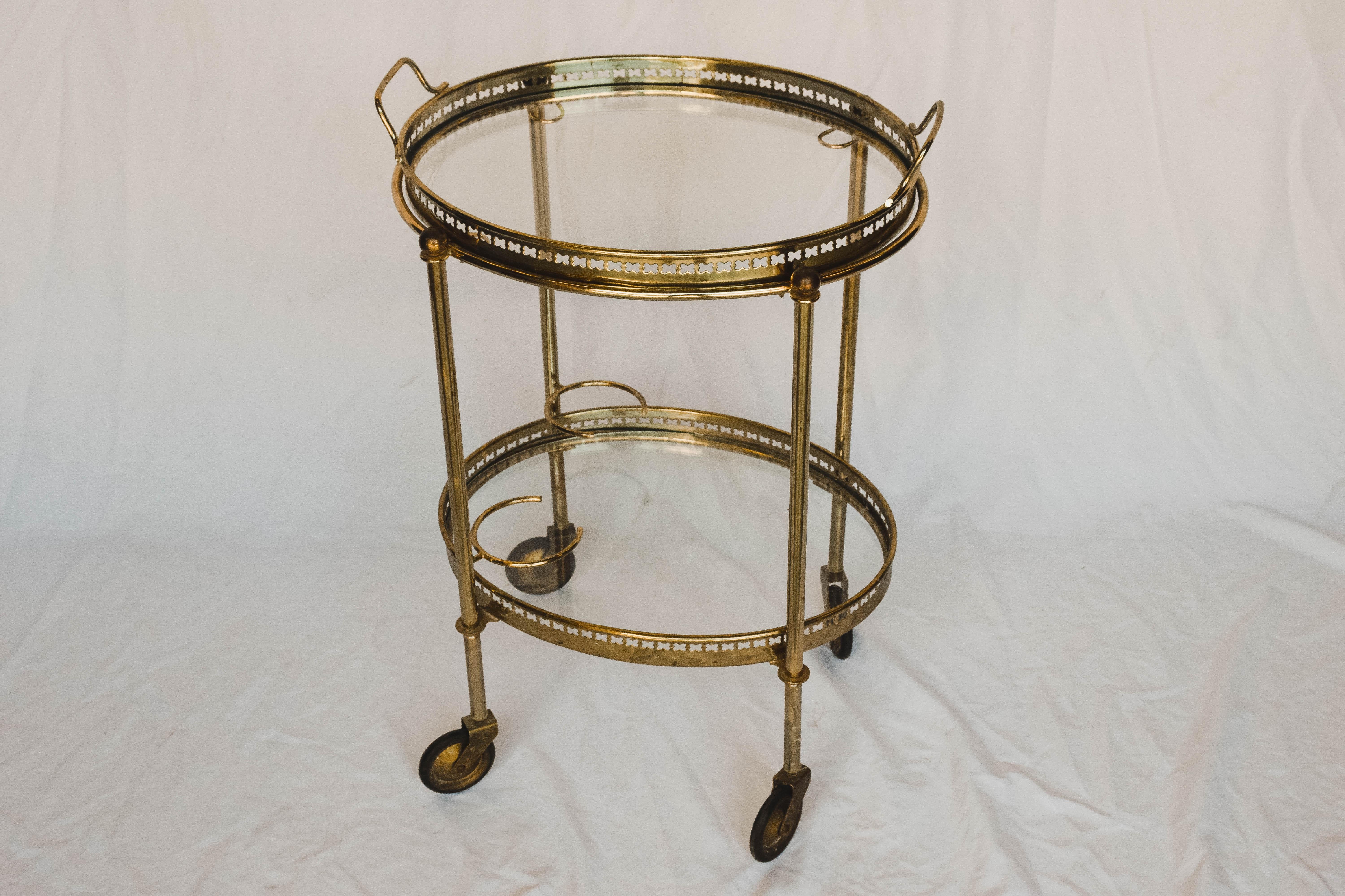 Stylish oval brass bar cart - Serving trolley with removable tray and bottle holders.
This two-tier drink trolley has two original clear glass shelves the upper one is also a removable serving tray with handles to carry. This bar cart has stylish
