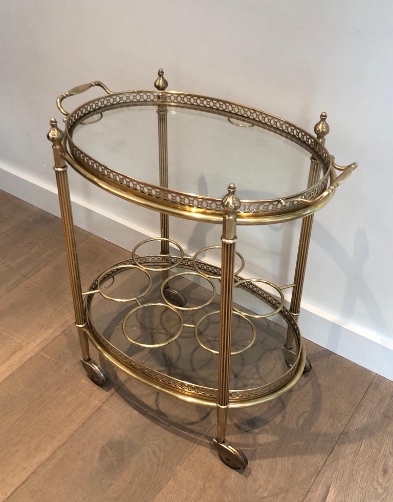 This oval bar cart is made of brass. It has a removable top tray and bottles holder on bottom tray. This is a French work by Maison Jansen. Circa 1940.