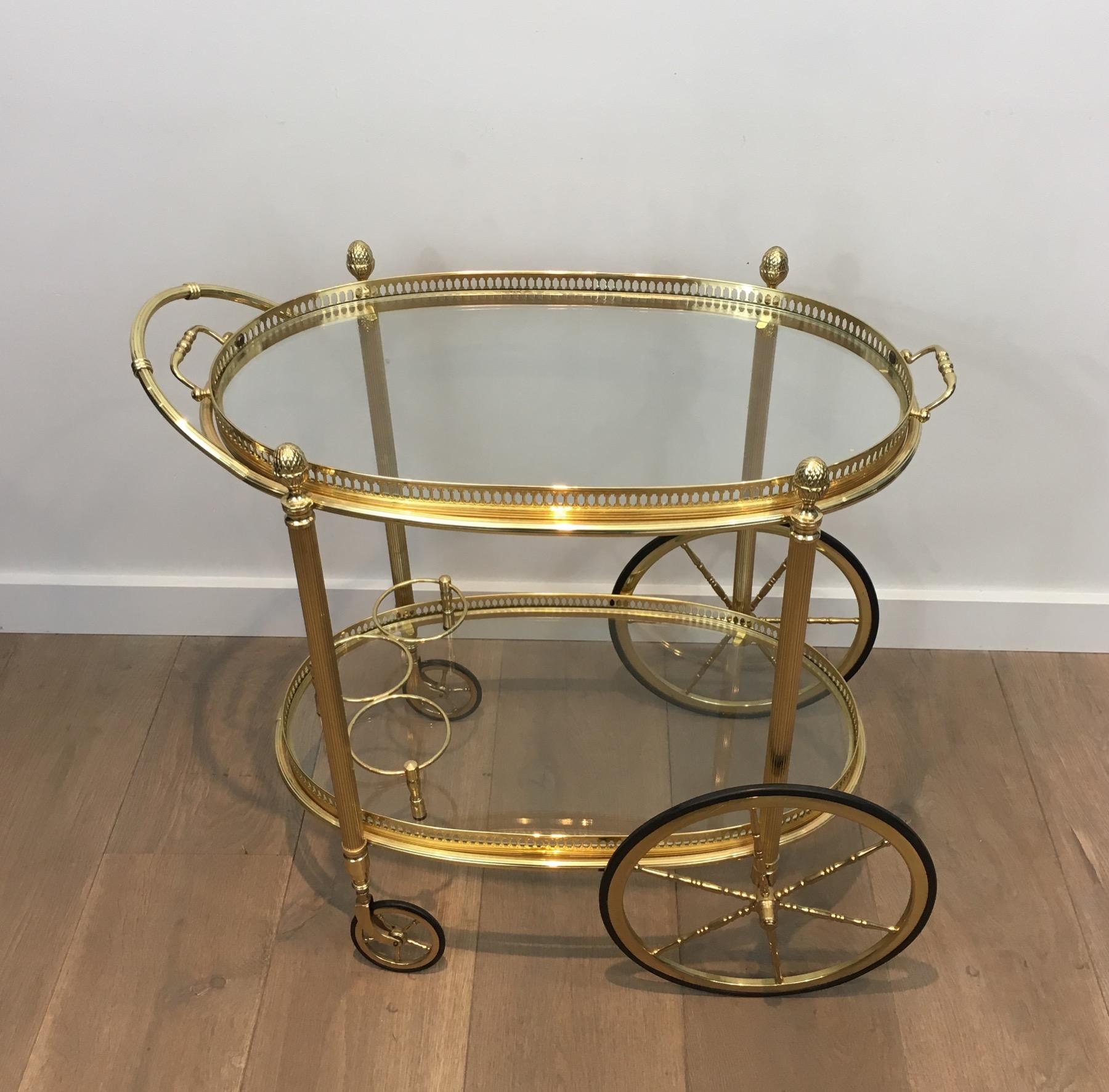 This very nice and elegant neoclassical Style Oval Drinks Trolley is all made of brass with fluted legs, large finials and removable glass trays. This is a French work by Maison Bagués. Circa 1940