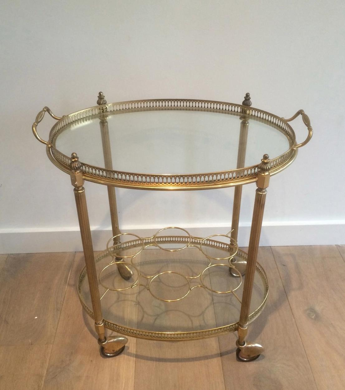 This elegant oval drinks trolley is made of brass with glass shelves. Top tray is removable and there is a bottles holder on the bootom shelf. This is a French work in the style of Maison Jansen. Circa 1940