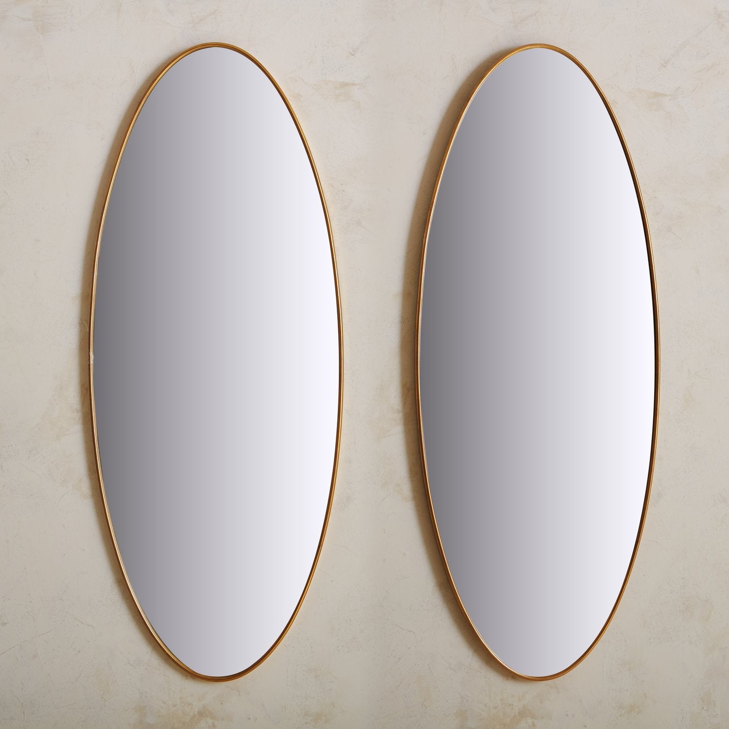 A vintage Italian mirror featuring an elongated oval shape with a delicate brass trim. This elegant piece has a wood backing and hardware for hanging. Sourced in Italy, 20th Century. One Available, Priced Individually.