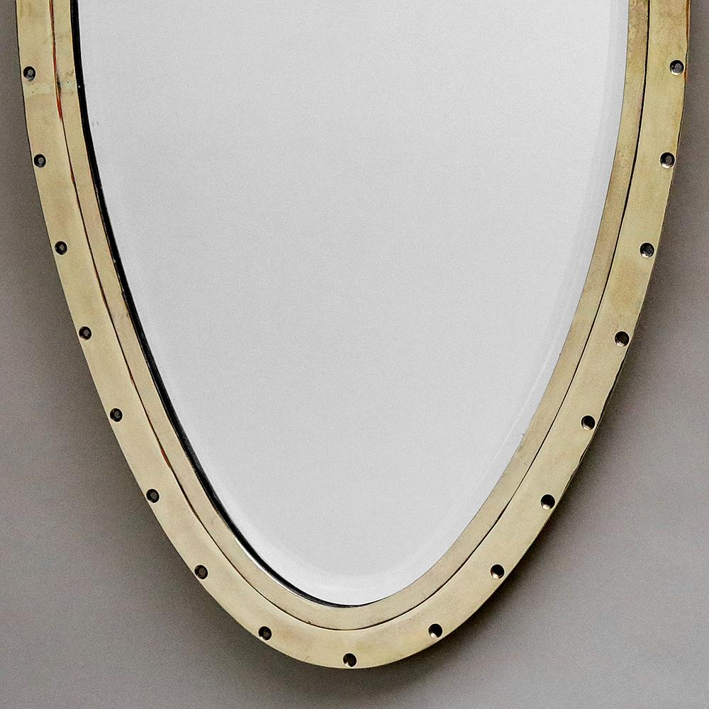 Unusual tapered oval brass mirror with beveled glass and distinctive detailing.