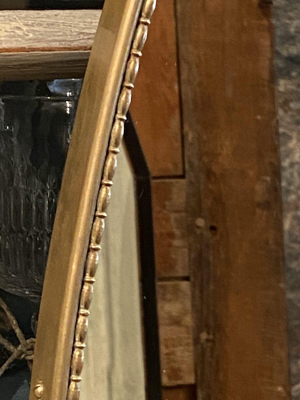 Elegant and stylish Italian midcentury brass framed mirror. Wonderful oval profile and a simple chain of elongated beading around the frame, and beautiful patina. Original mirrored glass, and style wise attributed to the designer Gio Ponti.