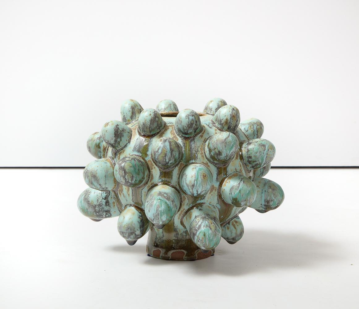 Grès émaillé.  Vase à pied de forme ovale avec des formes appliquées et des glaçures bleues.   Signature de l'artiste sur la face inférieure.