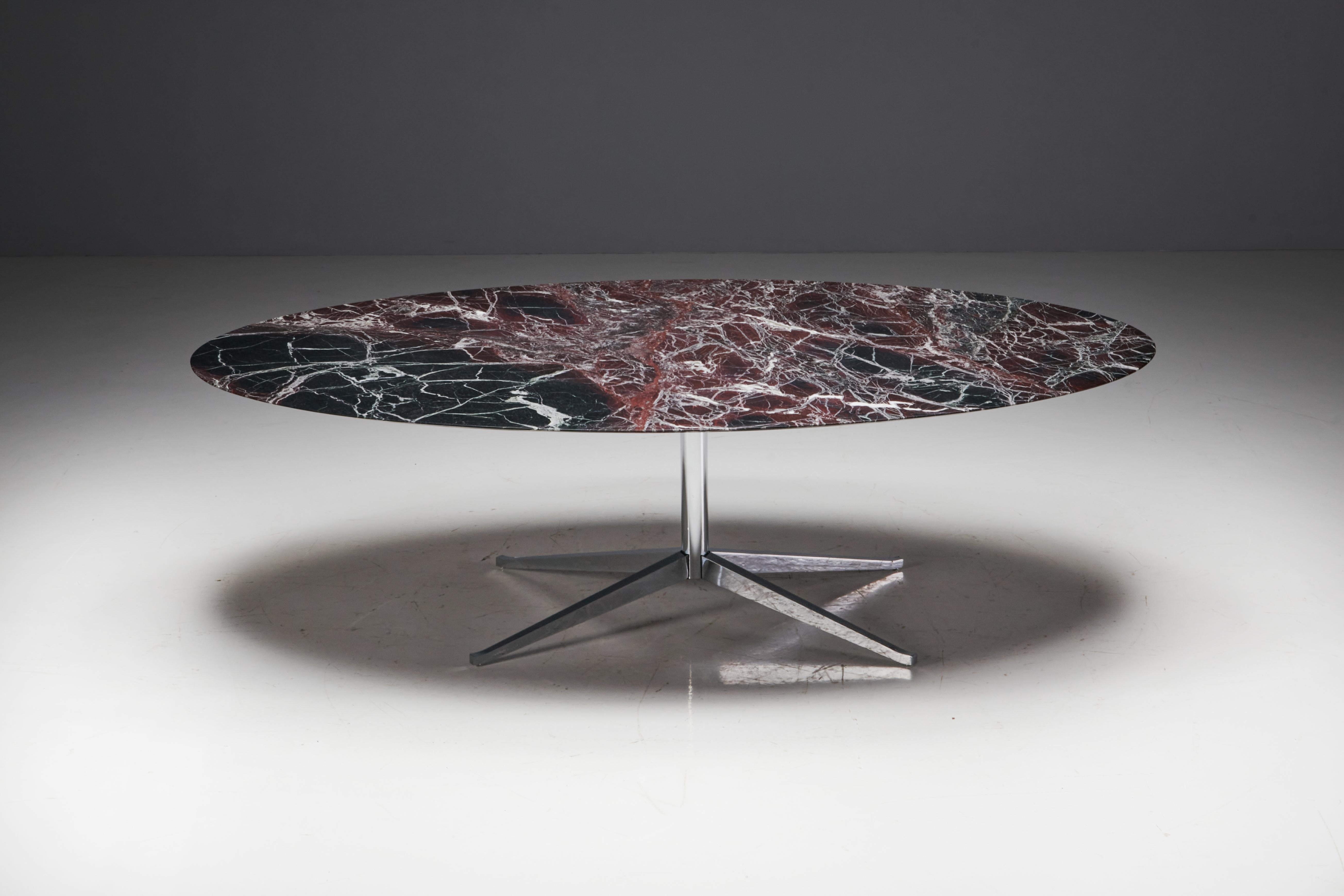 Oval burgundy marble dining table by Florence Knoll, manufactured in the United States during the 1960s. The tabletop, hewn from solid burgundy marble, rests gracefully on a steel base supported by four splayed legs. The marble exhibits exquisite