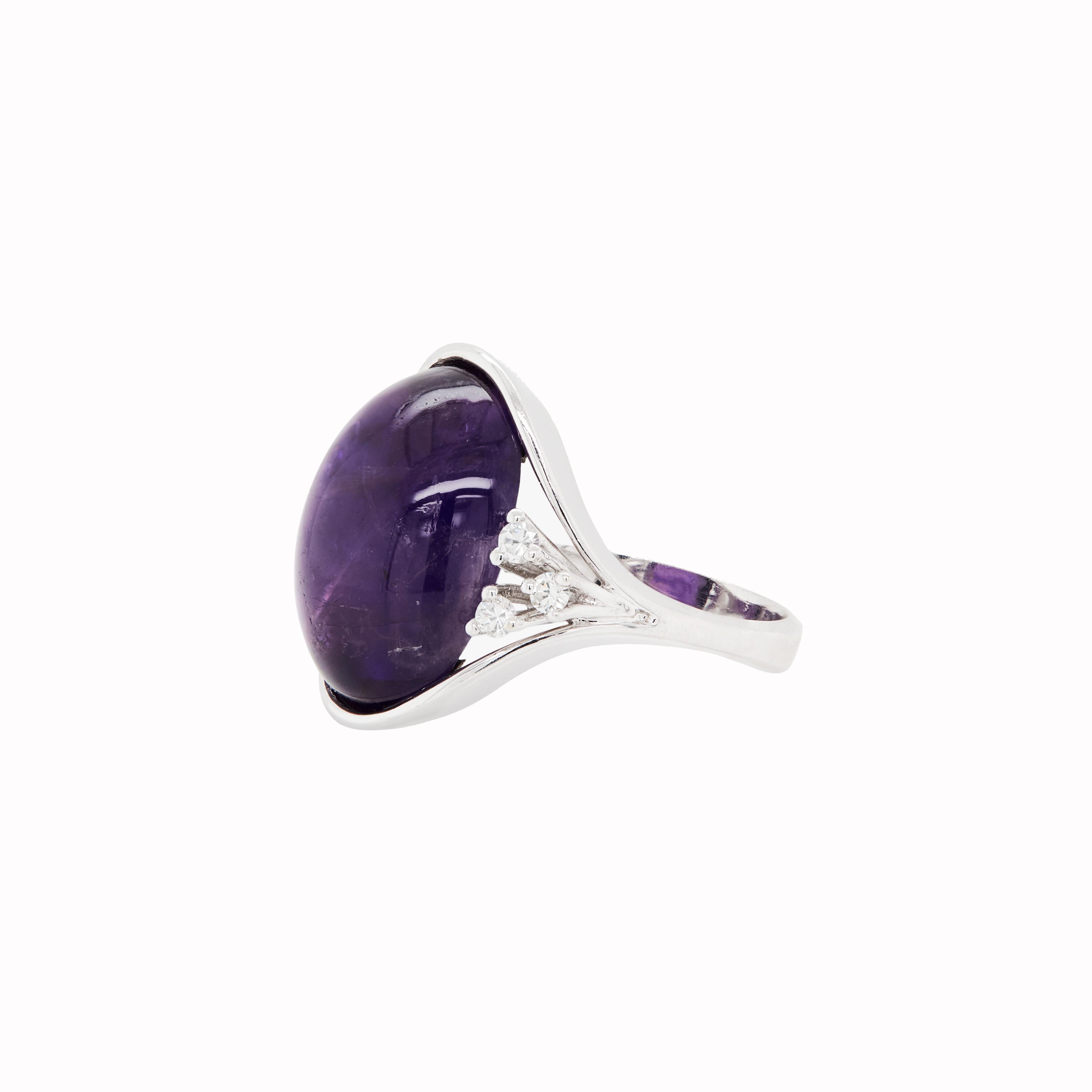 This stunning dress ring is a perfect blend of elegance and rich, captivating colour.

At its heart lays a beautifully smooth, deep purple amethyst cabochon, semi rub-over set in cool 18 carat white gold.

Adding to its charm, 6 high quality round