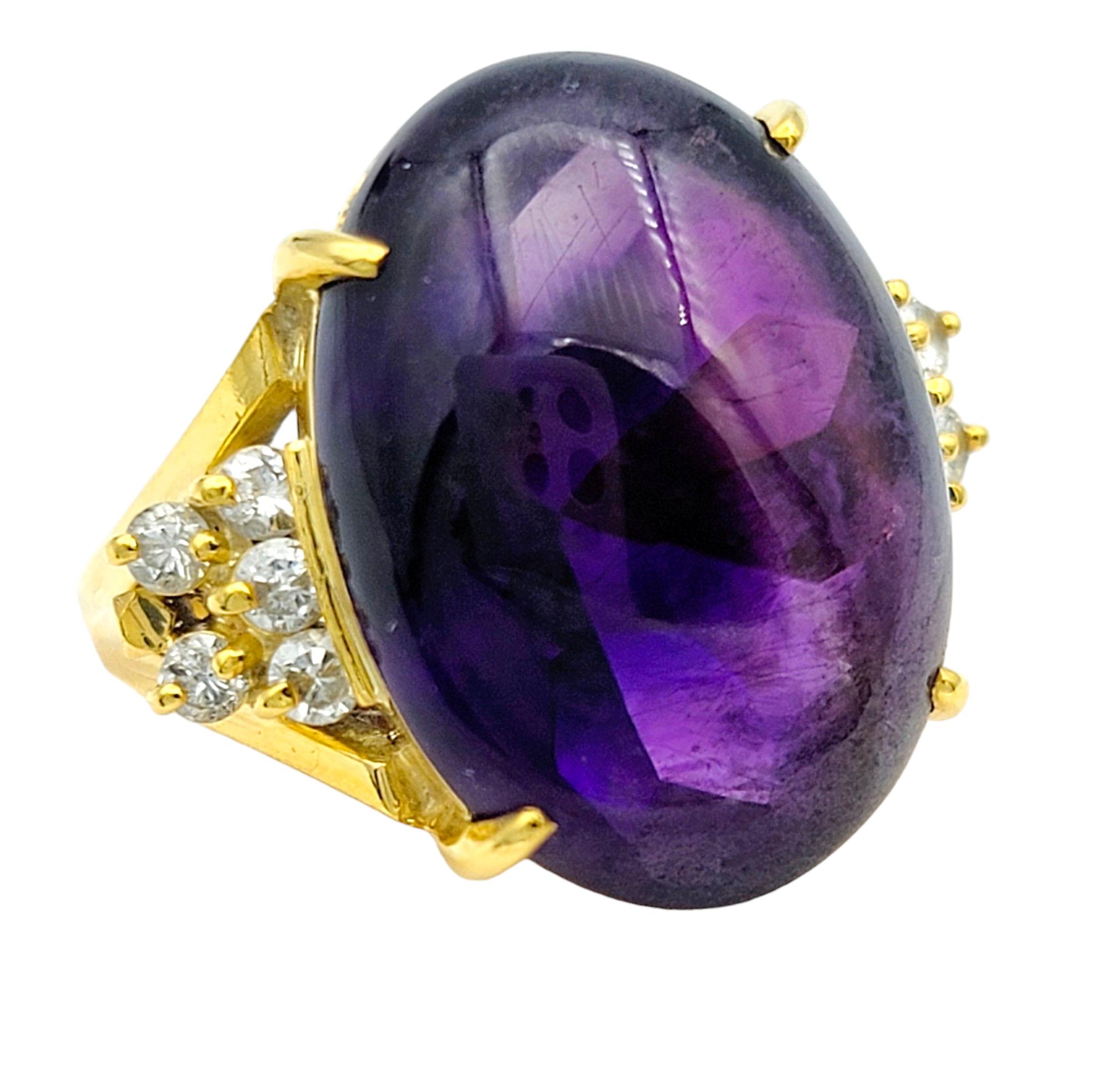 Ring Size: 4.75

This charming ring features a captivating oval cabochon amethyst embraced by shimmering diamonds on each side, all set in radiant 18 karat yellow gold. The rich purple hue of the amethyst gemstone exudes a sense of sophistication
