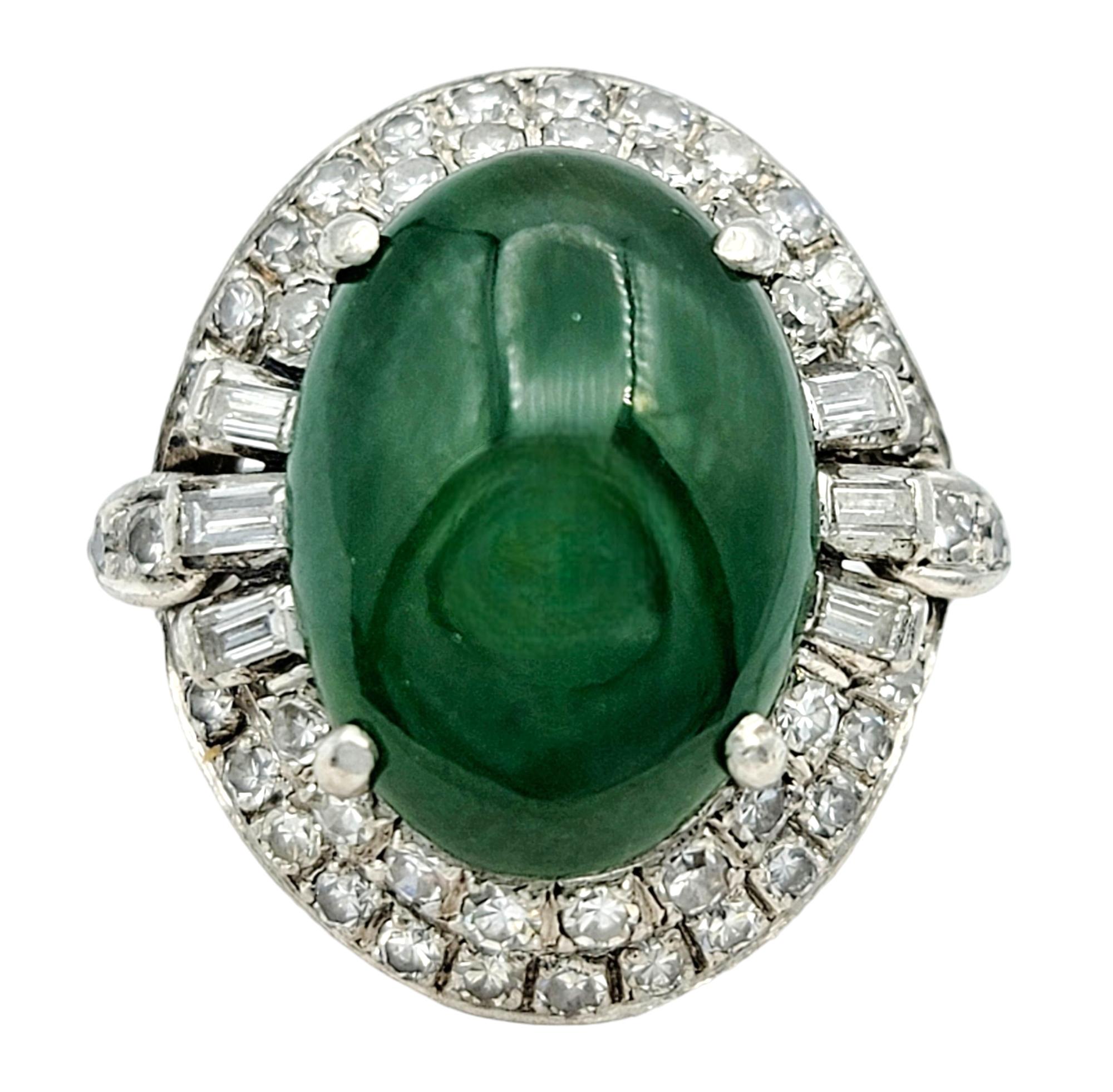 Ring Size: 4.75

This luxurious oval green cabochon cocktail ring is adorned with a double diamond halo and set in platinum. This exquisite ring features a captivating green cabochon at its center, its smooth surface showcasing the rich hue of the