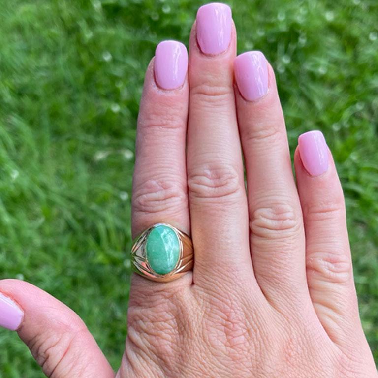 Oval shape cabochon green jade ring, bezel set in 14k yellow gold. The Jade measures approximately 16.20 mm x 11.37 mm x 5.30 mm with an estimated weight of 8.8 carats. The ring has a rounded tapered shank with a high polish finish with a geometric