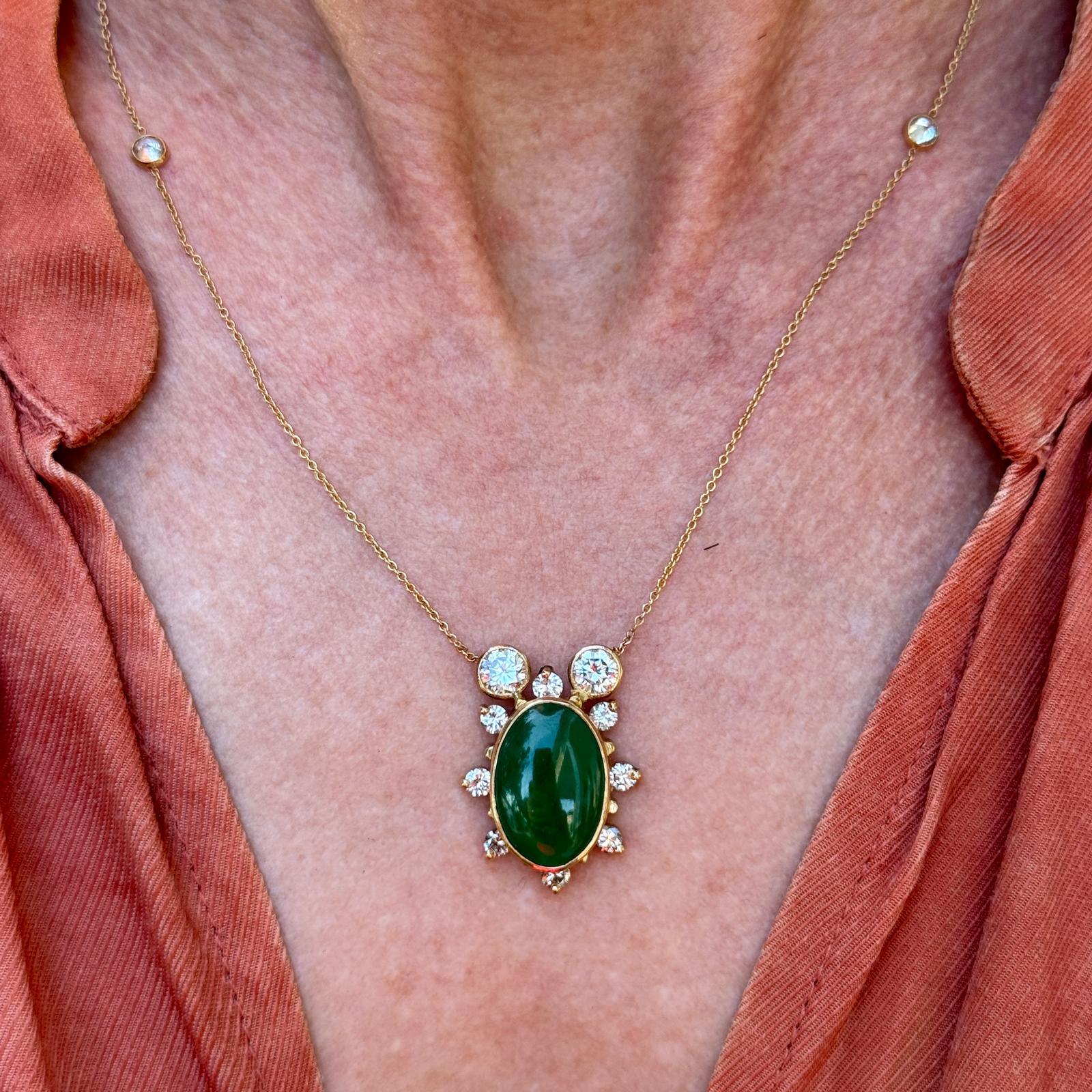 This contemporary 14 karat yellow gold pendant necklace features an elegant oval cabochon jade centerpiece, exuding a rich, natural hue. Surrounding the jade are sparkling diamonds totaling 2.40 carats, graded HI/SI, adding brilliance and