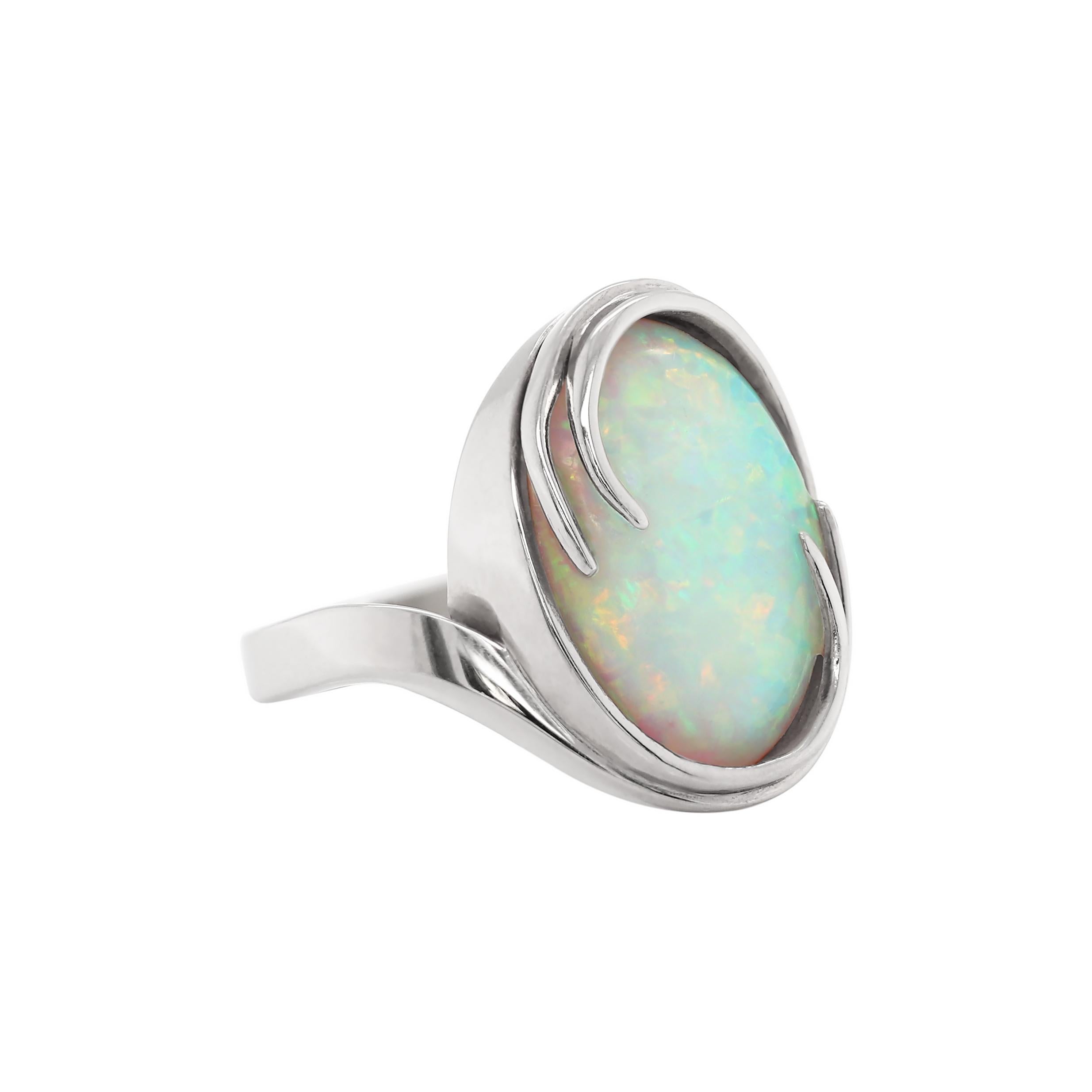 This beautifully modern handmade ring features a lustrous oval cabochon opal weighing an estimated 5.68ct mounted in an 18 carat white gold rubover, open back setting. UK finger size 'N'.