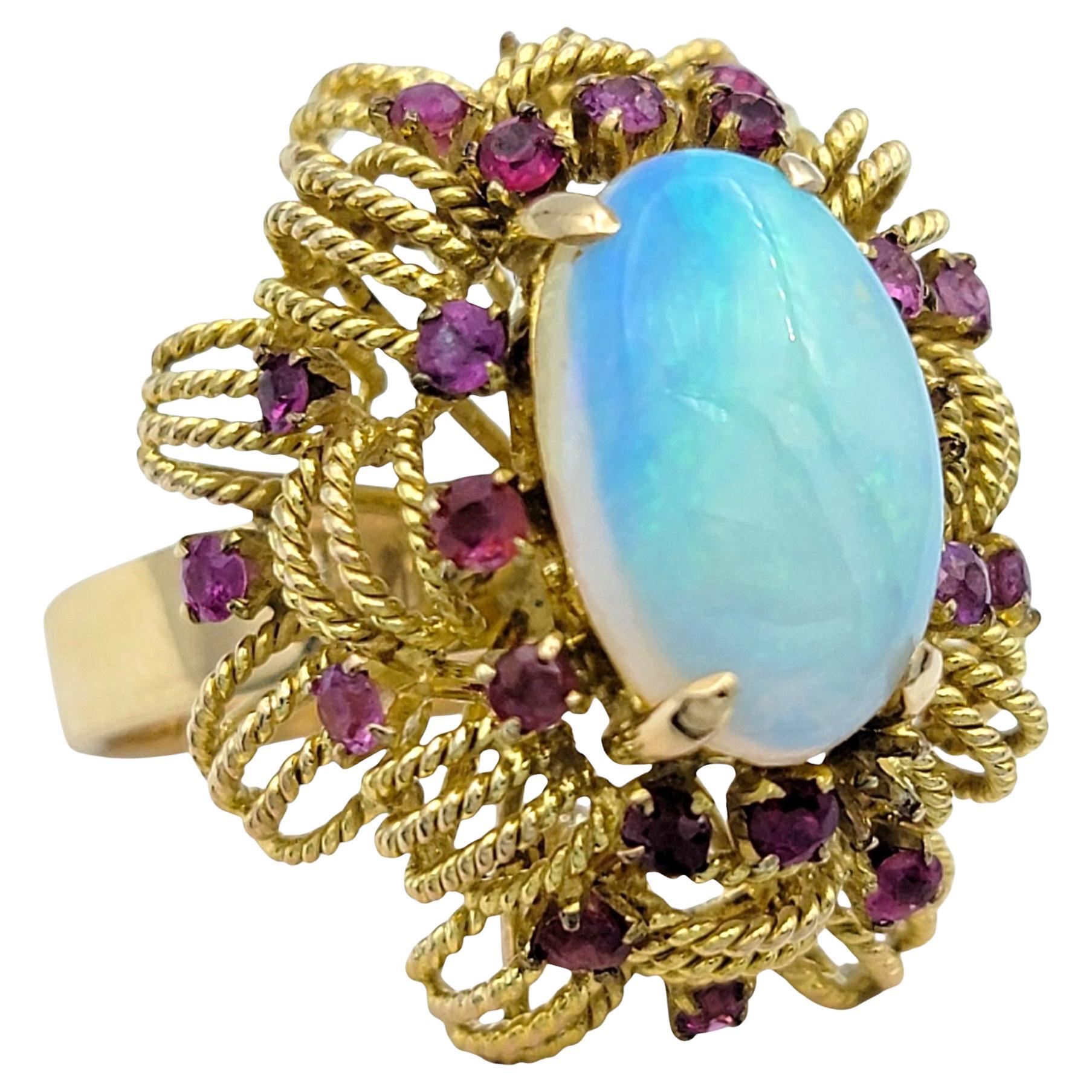 Ring Size: 7.75

A mesmerizing display of color and elegance, this opal and ruby halo ring is a statement of refined luxury. At its center, an enchanting oval-cut opal glows with a captivating play-of-color, shifting between vibrant hues that dance