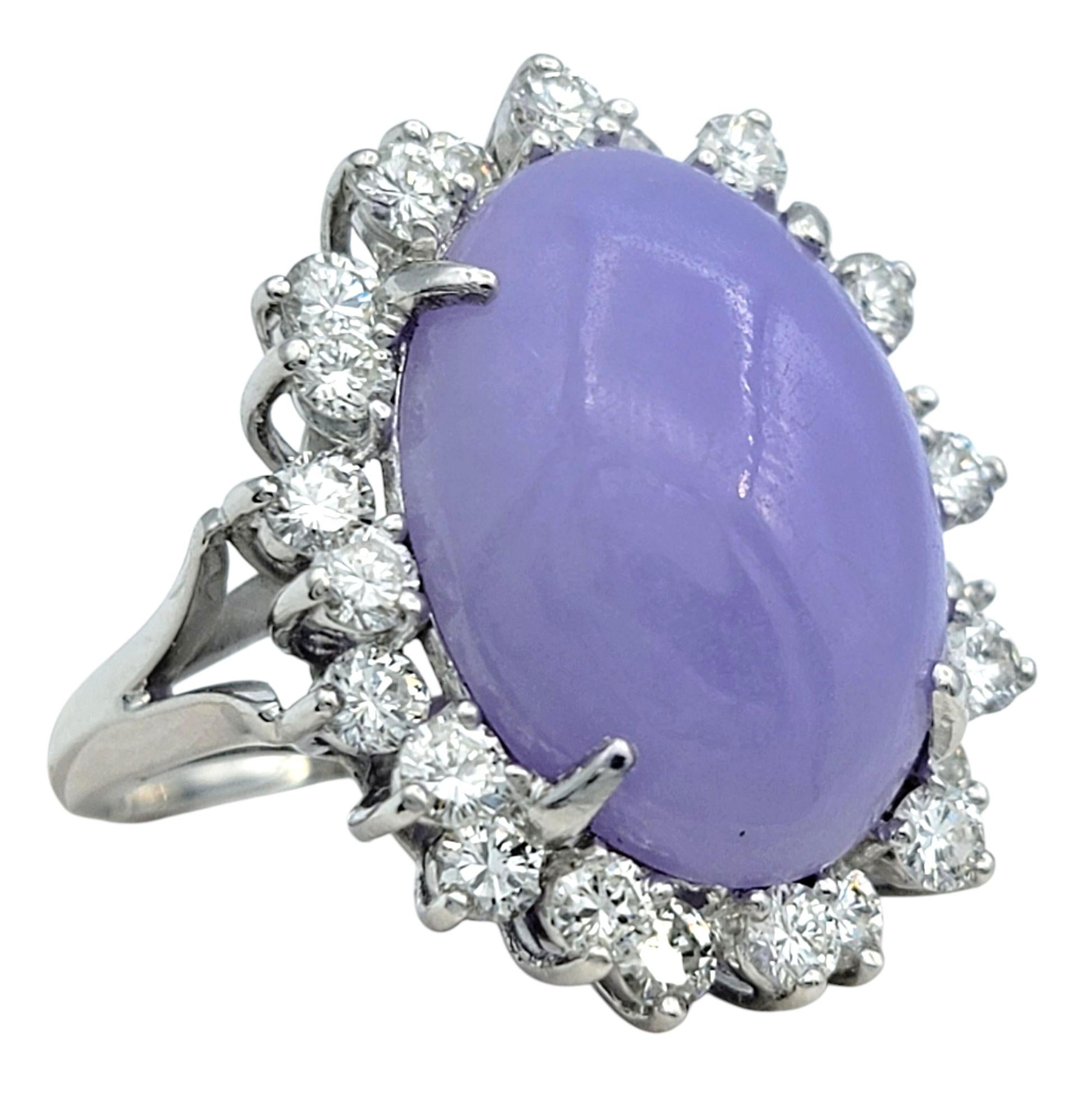 Ring Size: 4.75

Bold and captivating, this cocktail ring centers on a vibrant purple oval cabochon-cut dyed jade, set in gleaming 18 karat white gold. The richly hued centerpiece is encircled by a halo of sizeable round brilliant cut diamonds that