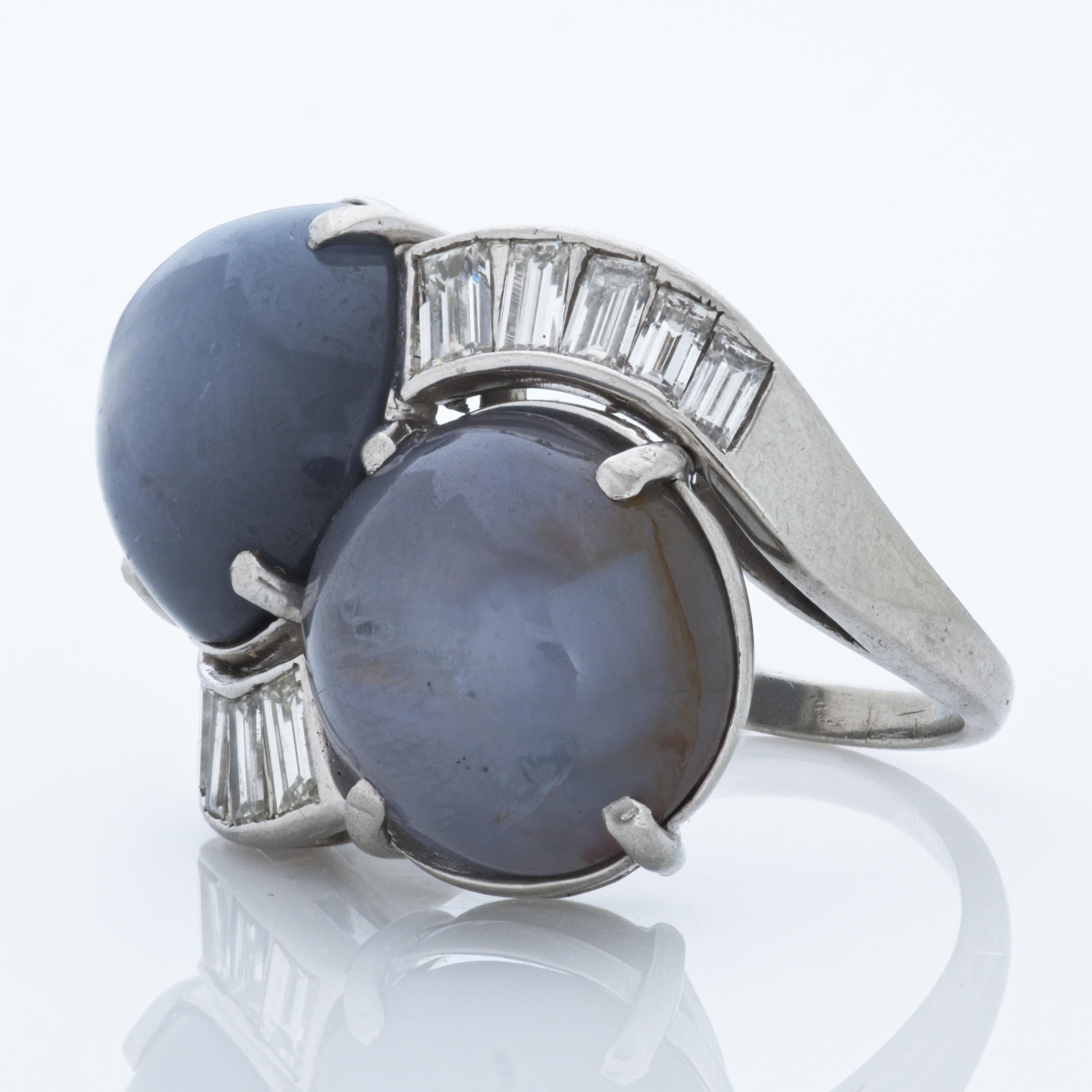 Oval cabochon star sapphire and baguette diamond twin bypass ring in platinum.

This ring features two oval cabochon star sapphires totaling approximately 27.00 carats.  These sapphires are accented by 10 baguette shape diamonds totaling