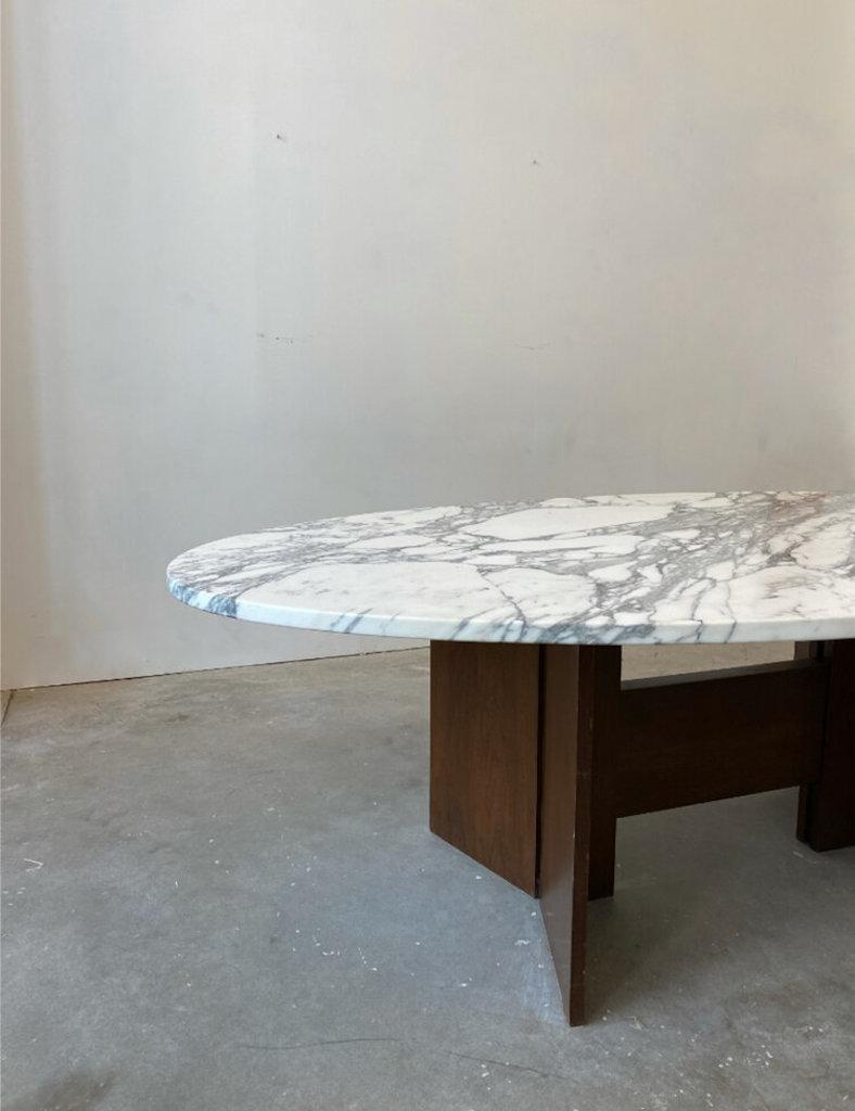 A mid-century oval calacatta marble top dining table with a mahogany base. The base is sculptural, sturdy and beautifully supports the ultra heavy and substantial marble top. The oval top is 1” thick and has a slightly beveled edge. We sanded and