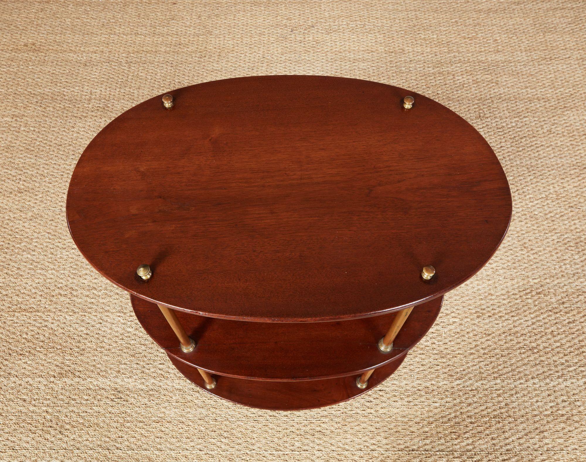 Etagère de campagne ovale anglaise, les trois étagères ovales en acajou soutenues par des colonnes en laiton à collet mouluré. Utile comme table d'appoint ou comme support de bar.