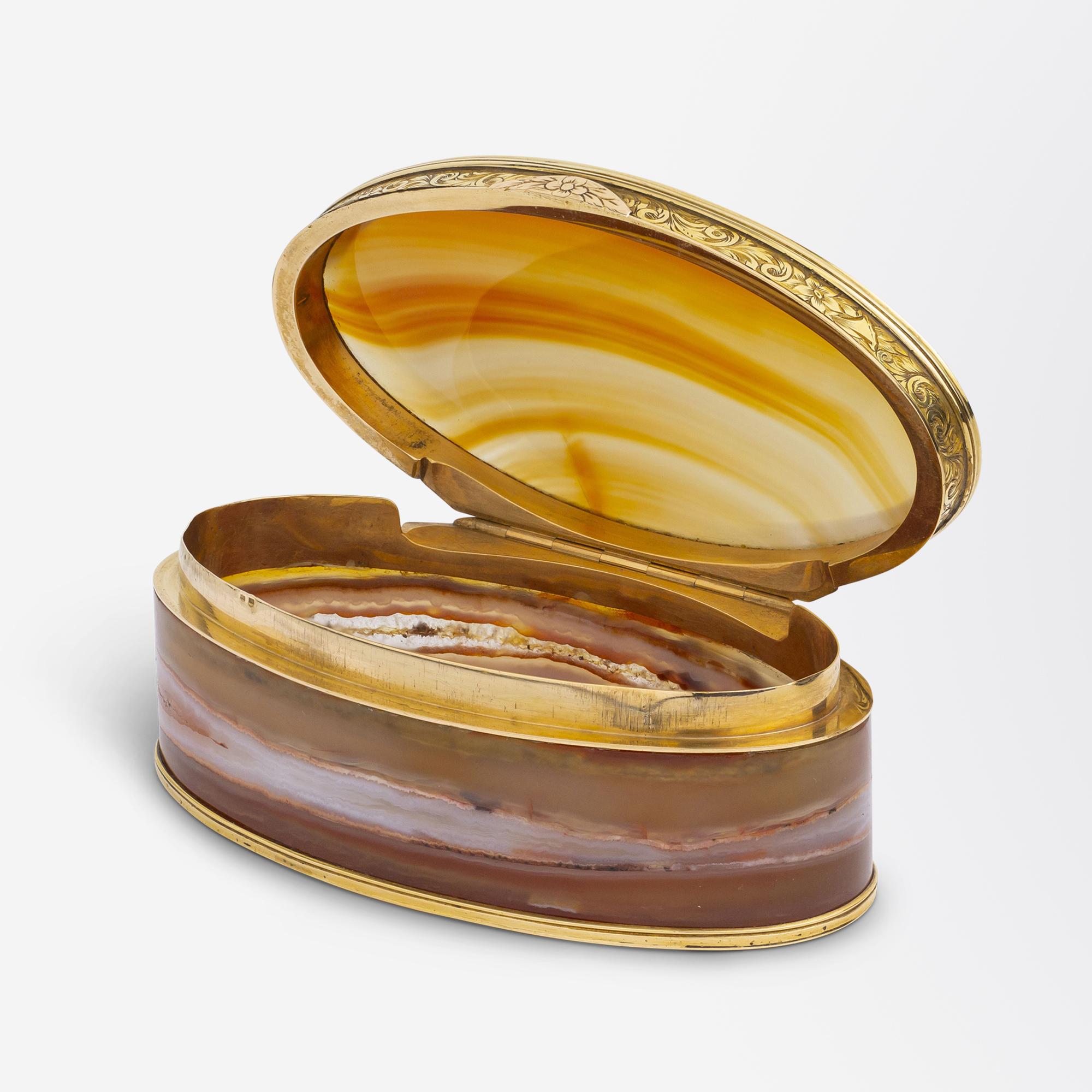 This carnelian agate and gold box was imported into France and is hallmarked with a French import mark. The oval box features what is likely 9 karat yellow gold mounts, which are on the bottom of the box, the top of the lid, and the inside of the