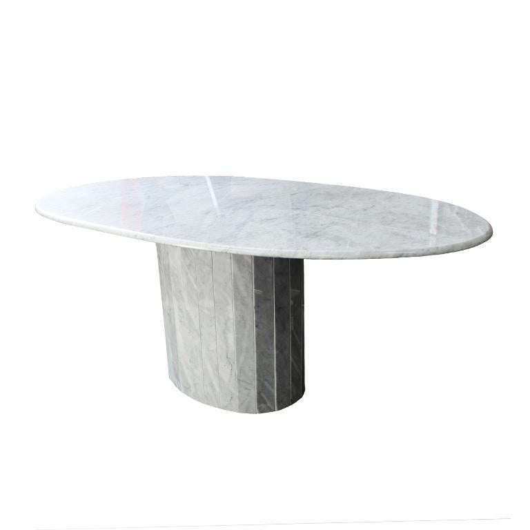 Oval Carrara marble dining table with beautiful gray veining and tessellated pedestal base. This lovely piece would be an excellent way to host guests for your next dinner party. The solid marble top is in an oval shape with slightly rounded edges.