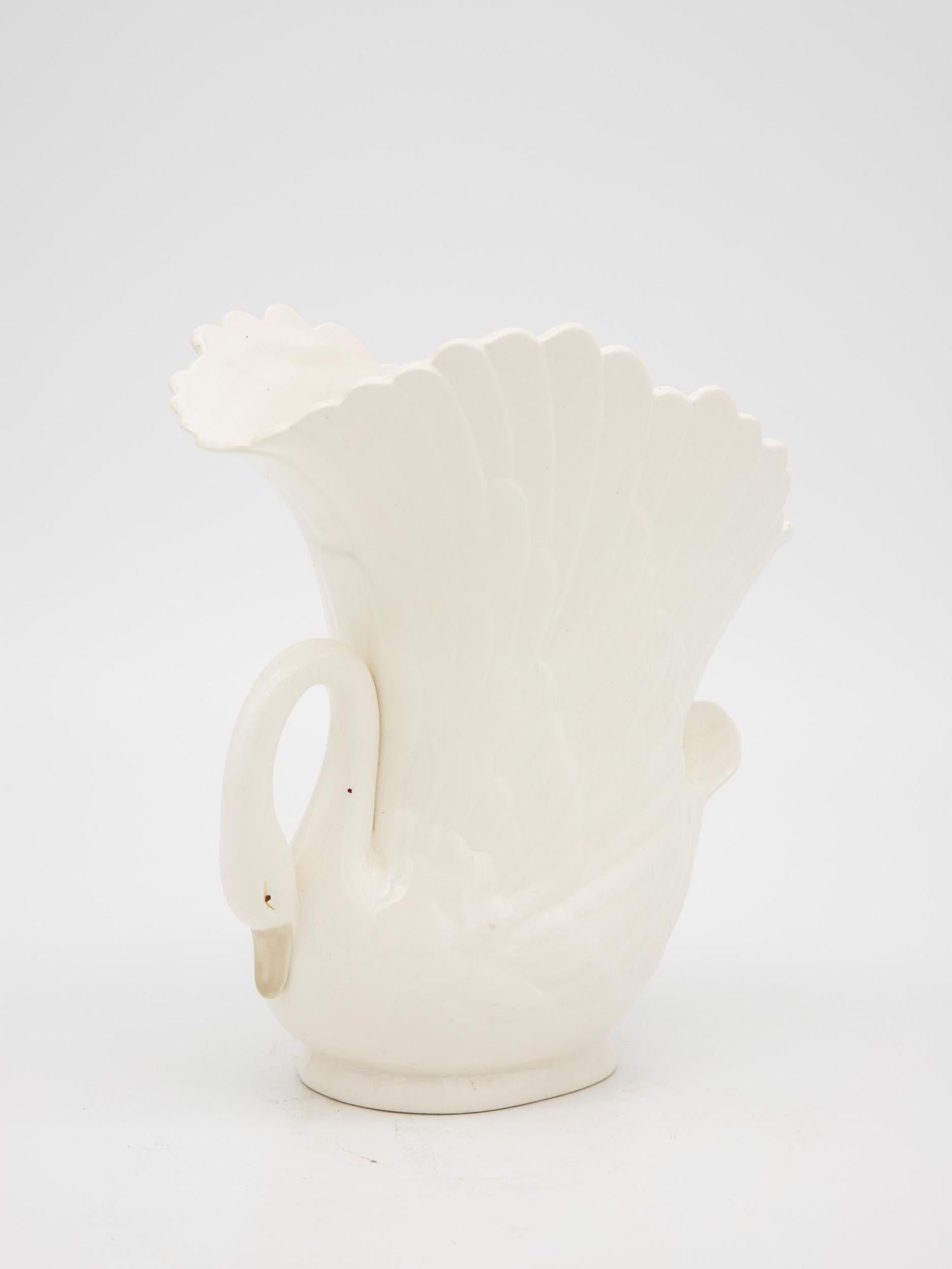 A late 20th-century small bisque ceramic swan vase with a gracefully arched neck that curls down to form a delicate handle. The beak and eyes are delicately painted, giving the swan a charmingly expressive face. Detailed feathering along the body