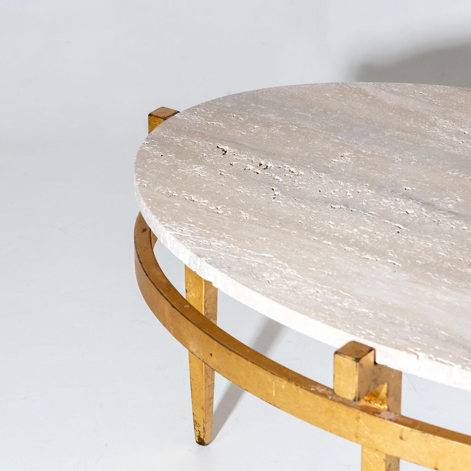 Two oval coffee tables crafted from gold-patinated metal featuring travertine tabletops. These tables are supported by elegant frames with tapered legs, adding a touch of sophistication. 
