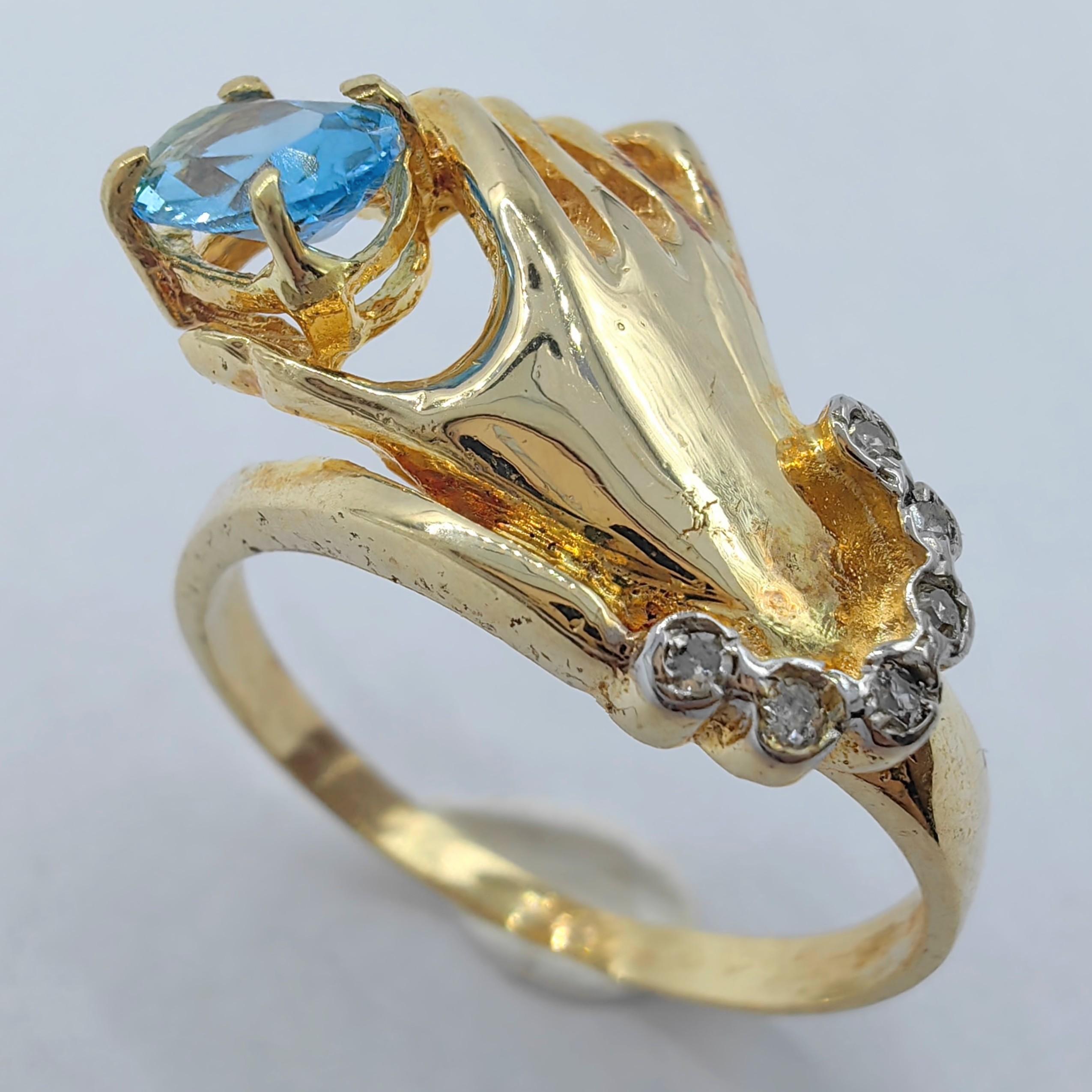 Unser exquisiter Blautopas im Ovalschliff in einem Hand-Diamantring aus 14 Karat Gelbgold ist ein Symbol für Eleganz und Anmut. Dieser einzigartige Ring zeigt ein wunderschön gearbeitetes Handmotiv aus 14-karätigem Gelbgold, das einen