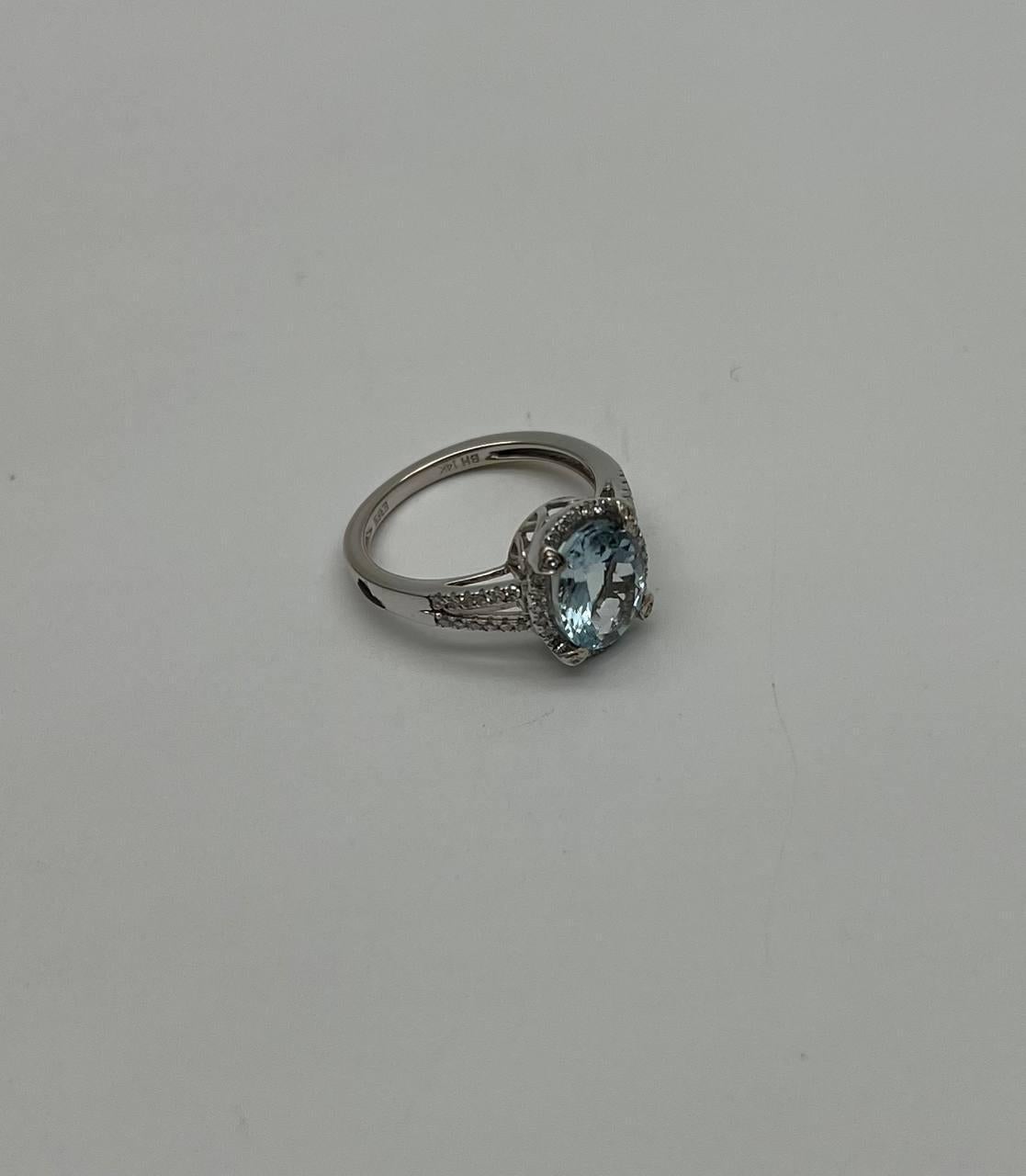 Elegant Aquamarine and Diamond Ring. This exquisite ring is crafted in a sleek metal setting. The center features a stunning oval aquamarine gemstone, surrounded by a halo of sparkling diamonds. The band is adorned with additional diamonds,