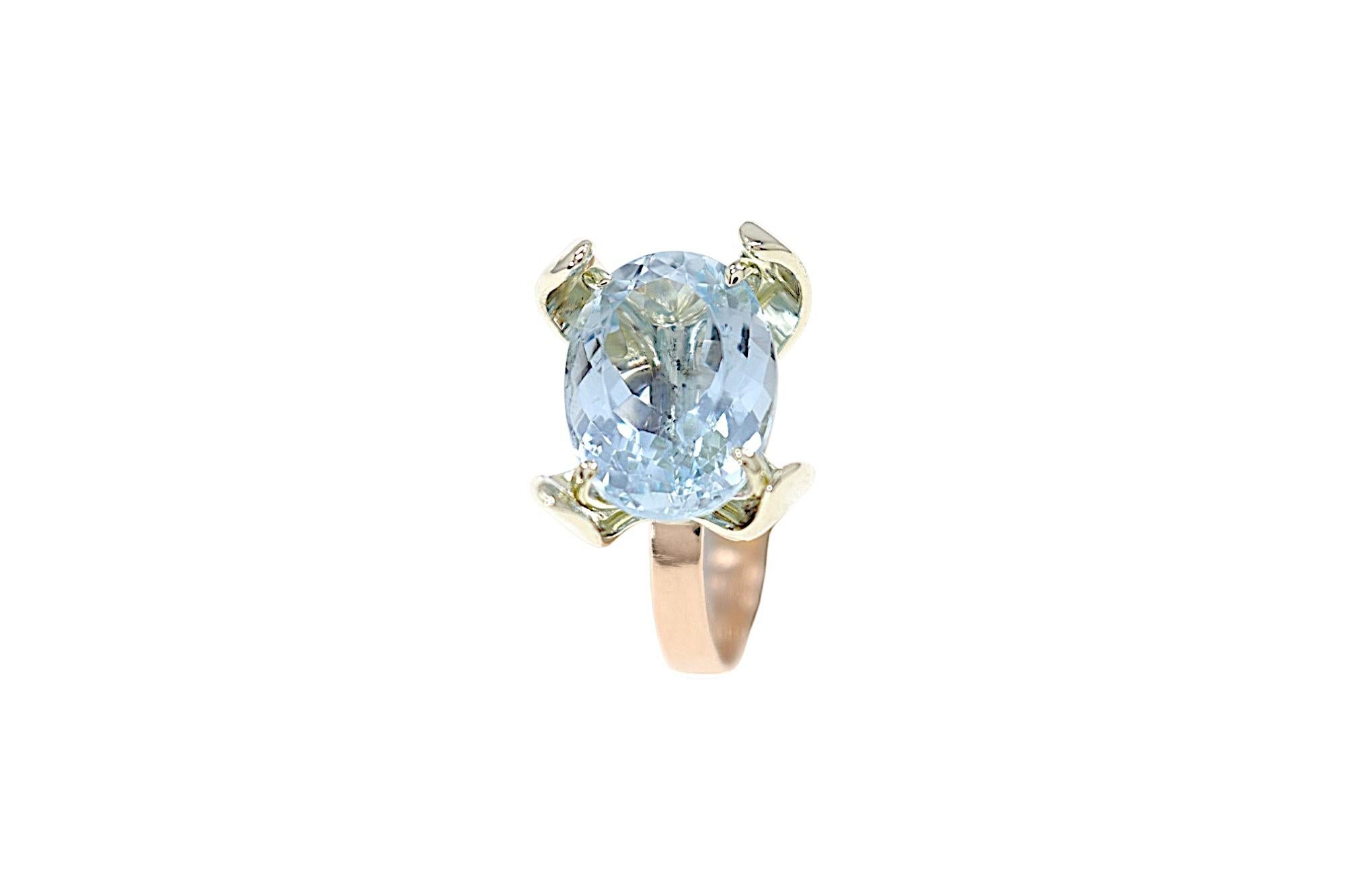 Extraordinary handcrafted ring in 9k white and rose gold featuring a stunning 6.45 ctw oval-cut aquamarine. The 4-prong stone setting is elegantly concealed by white gold petals forming a flower, with the elegant natural aquamarine sparkling at its