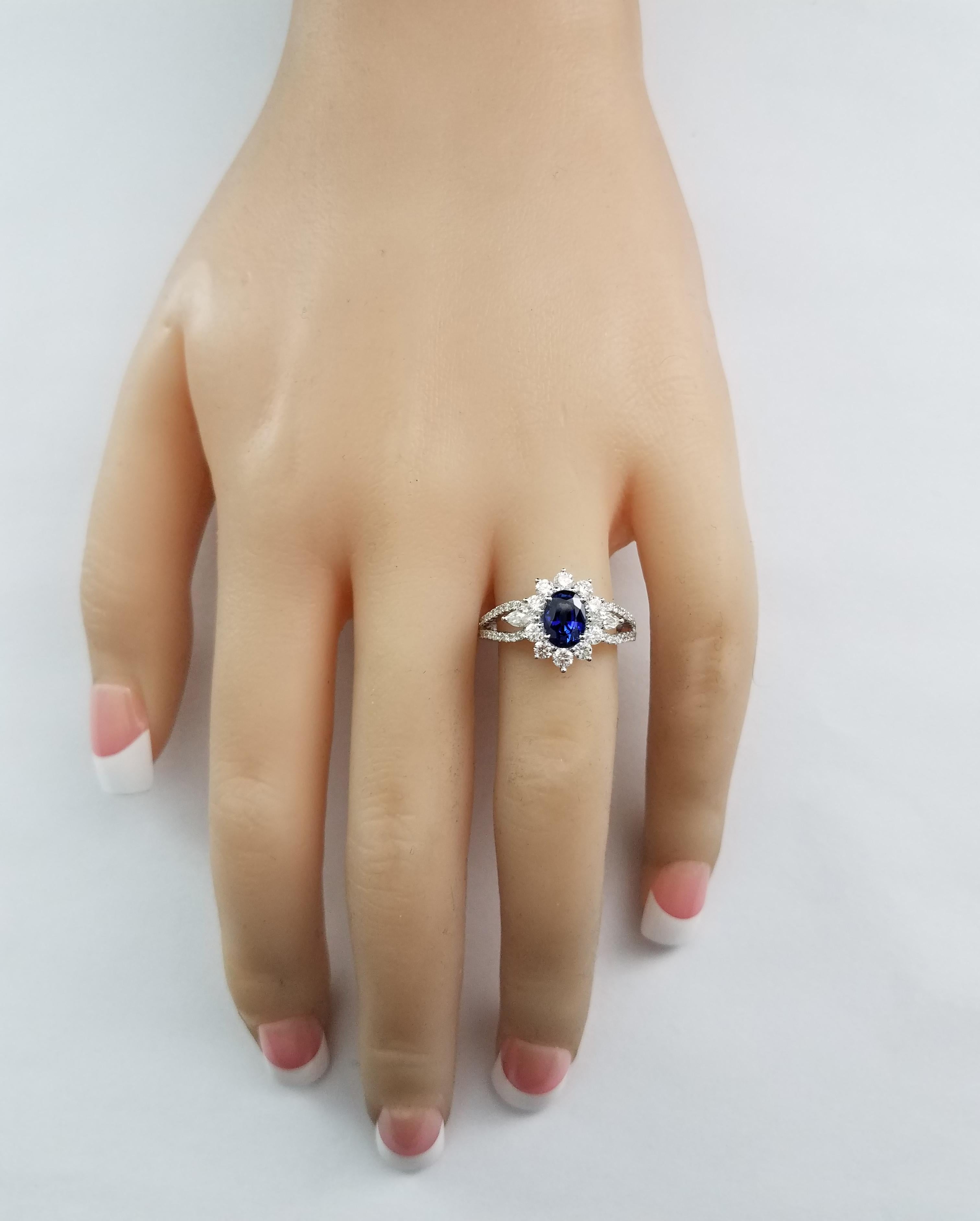 This elegant and vibrant engagement ring featuring 1.23 carat oval cut blue sapphire in the center, surrounded by 2 pieces of marquise cut diamonds and 50 pieces of brilliant round cut diamonds weighing 0.85 carat total, set in a split shank