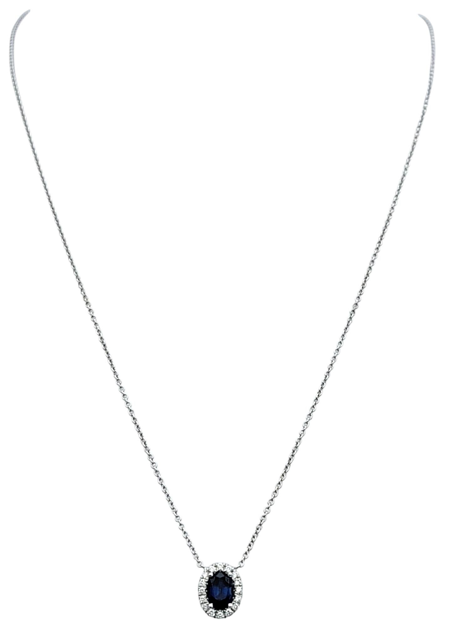 This stunning sapphire and diamond pendant necklace is a timeless piece of elegance. The centerpiece is a vivid oval-cut blue sapphire, set in luxurious 18 karat white gold. Surrounding the sapphire is a dazzling halo of round-cut diamonds,