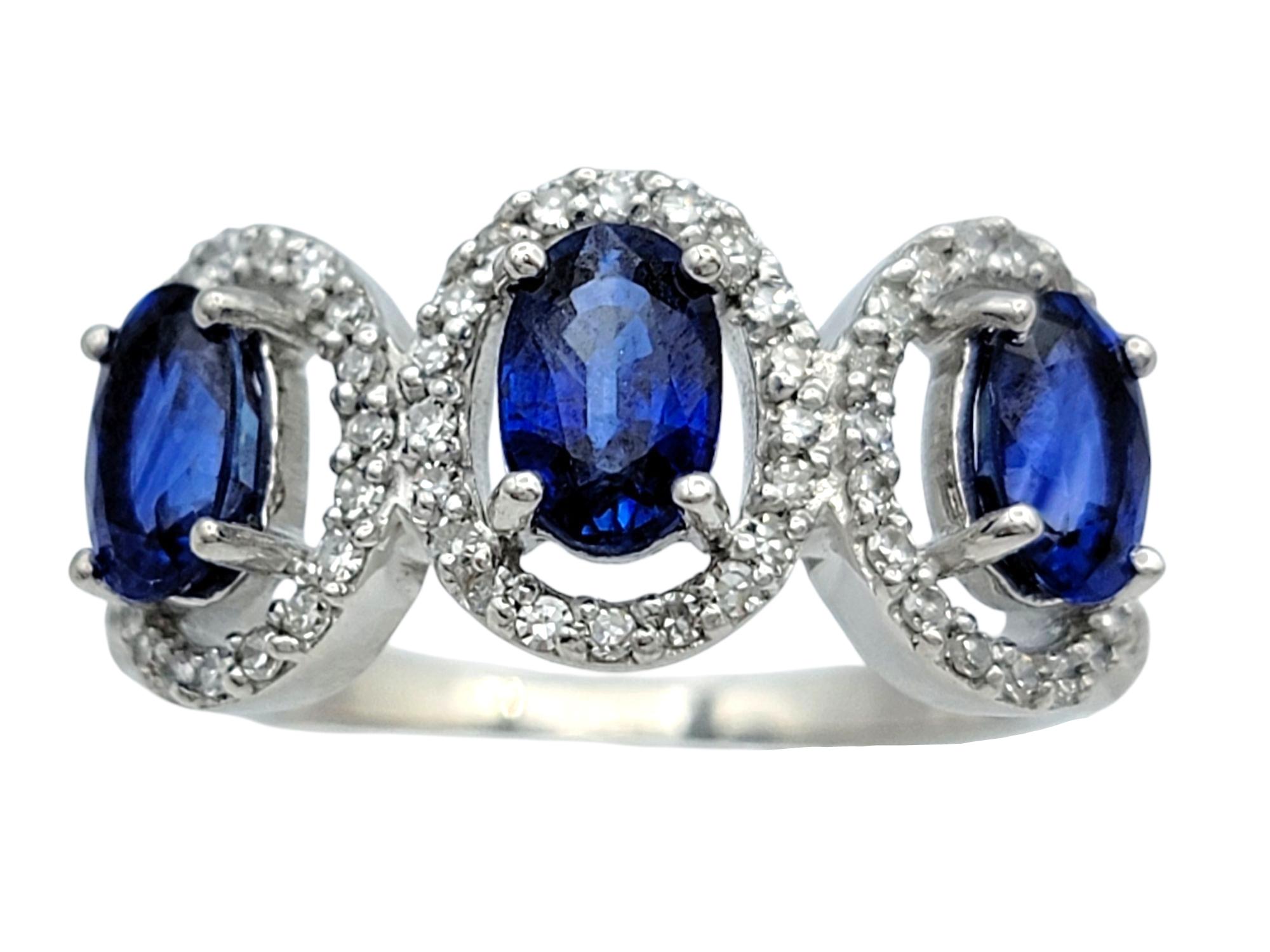 Contemporary Oval Cut Blue Sapphire and Diamond Halo Three Stone Ring in 18 Karat White Gold For Sale