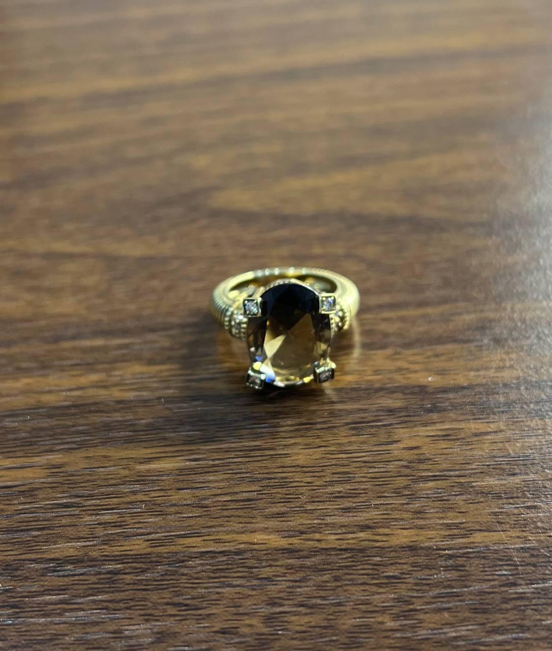 This remarkable piece, features a striking design in 14K yellow gold. The centerpiece is a large, faceted brown smoky quartz, held securely by four prongs, exuding a sense of luxury and sophistication. The band showcases intricate ribbed detailing,