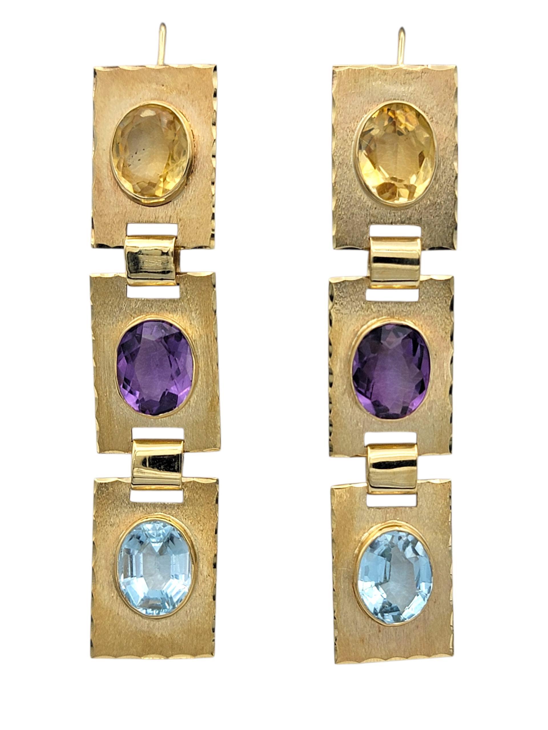 Diese Ohrringe sind mit einem vertikalen Trio aus bunten Edelsteinen versehen, das einen hellen, lebendigen Look erzeugt. An der Spitze sitzt ein warmer, gelber Amethyststein, der dem Design einen goldenen Glanz verleiht und es verankert. Direkt