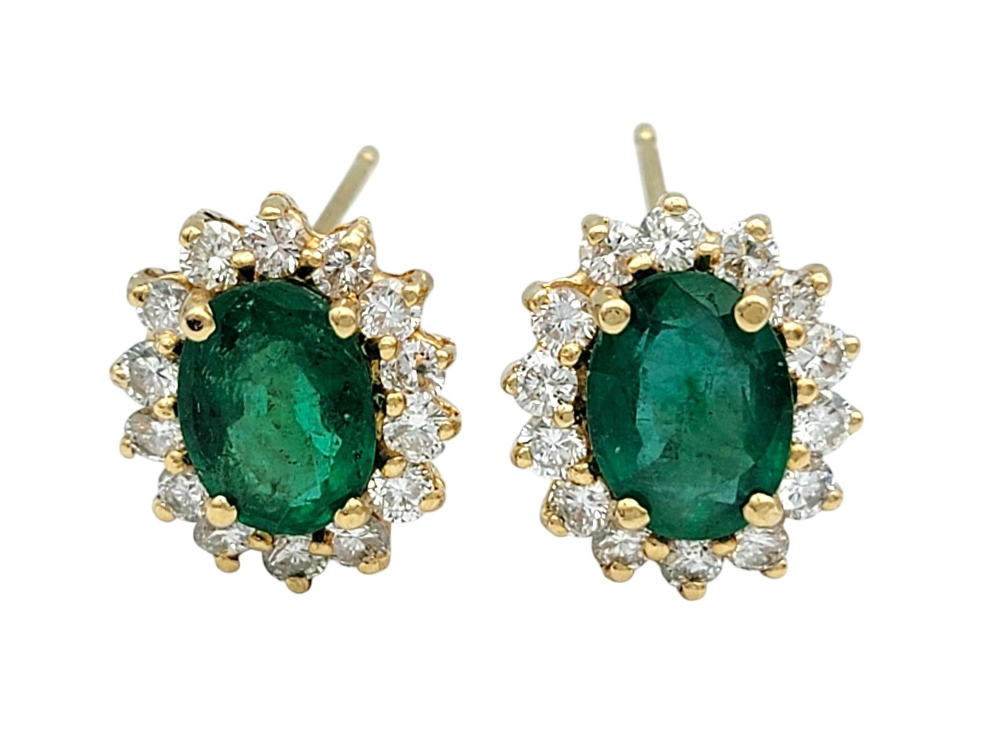 Contemporary Oval Cut Emerald and Diamond Halo Stud Earrings in Polished 14 Karat Yellow Gold For Sale