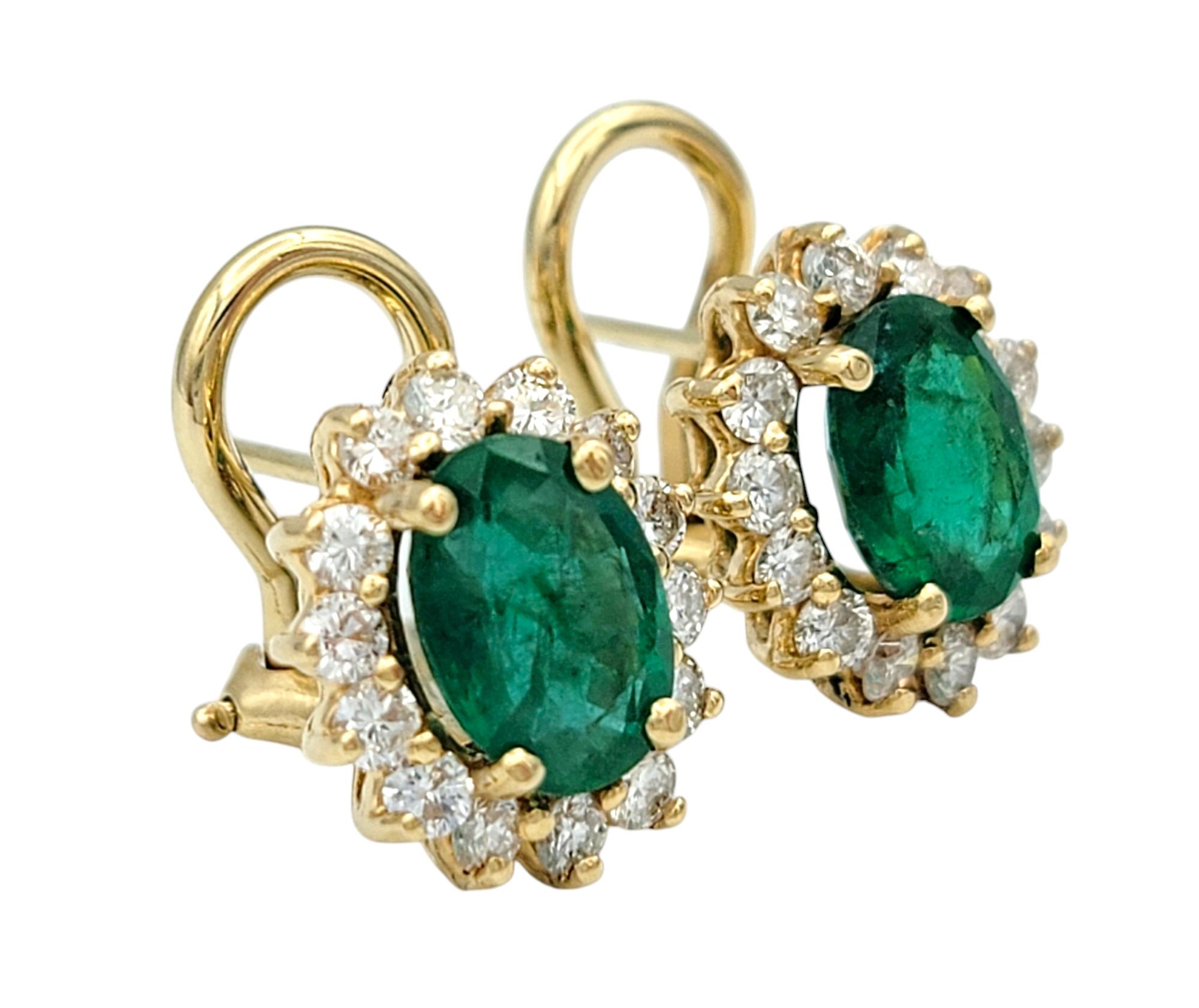 Women's Oval Cut Emerald and Diamond Halo Stud Earrings in Polished 14 Karat Yellow Gold For Sale