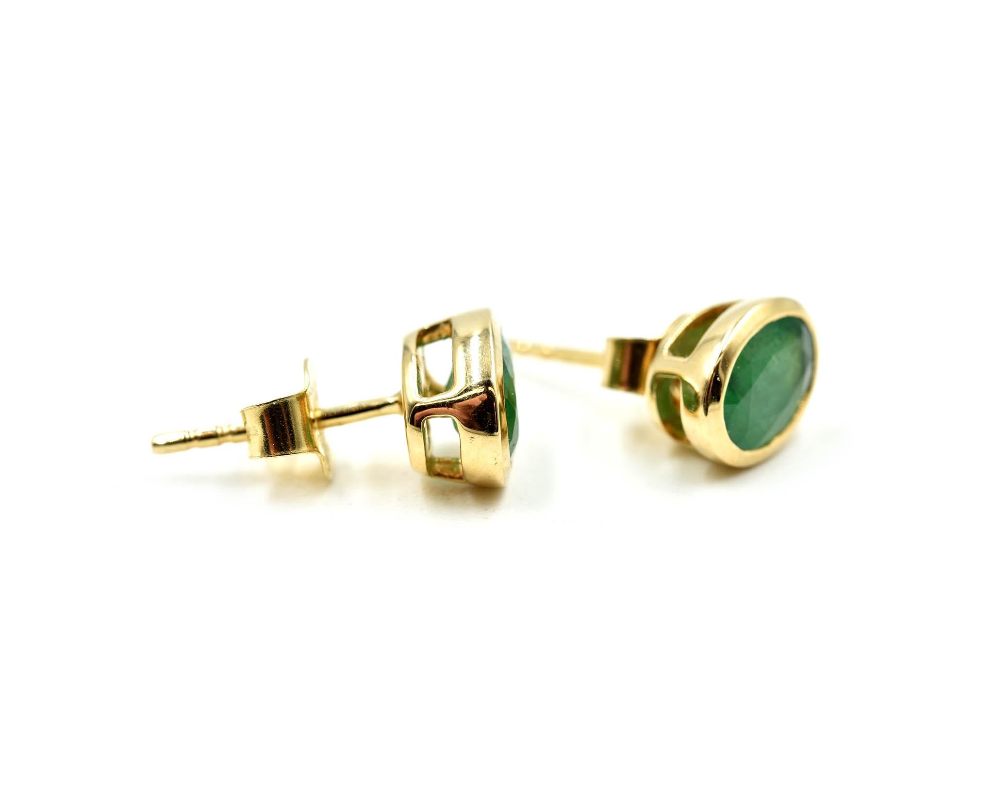 Designer: custom design
Material: 14k yellow gold
Emeralds: two oval cut emerald gemstones = 1.30 carat total weight
Dimensions: each earring measures 3/8 inches long and 1/4 inches wide 
Fastenings: friction backs
Weight: 2.20 grams
