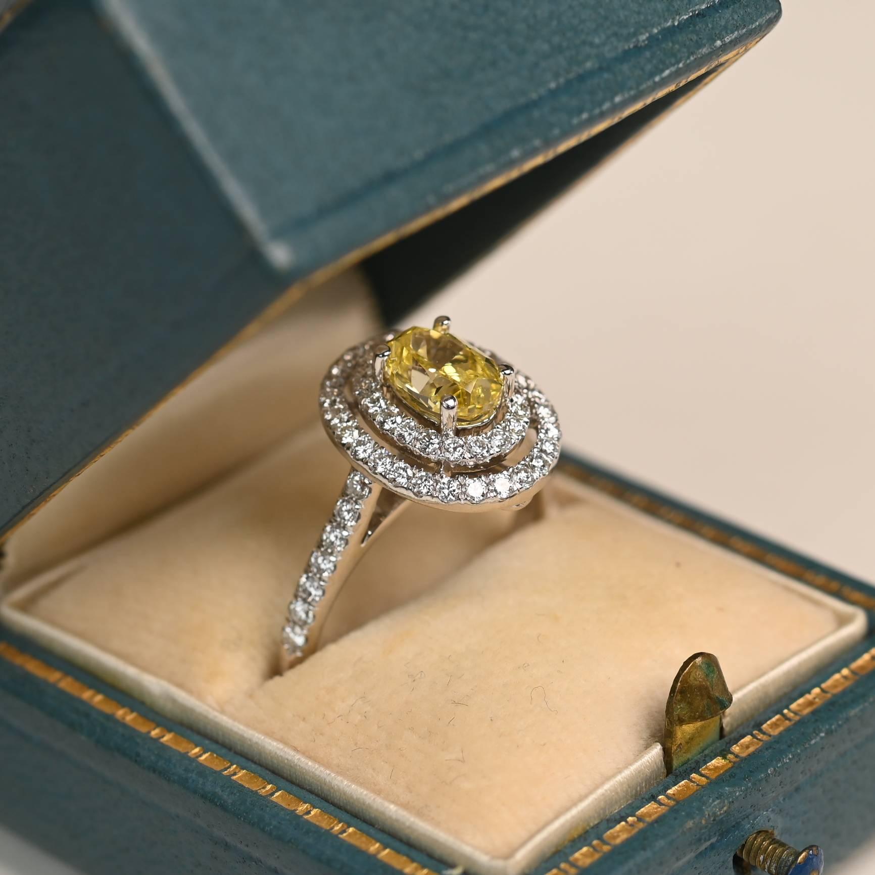 Questo anello di grande impatto presenta un diamante ovale di circa 1 carato, certificato GIA, incastonato in una montatura sicura. La vibrante pietra centrale è circondata da un'abbagliante doppia aureola di diamanti bianchi in una disposizione a