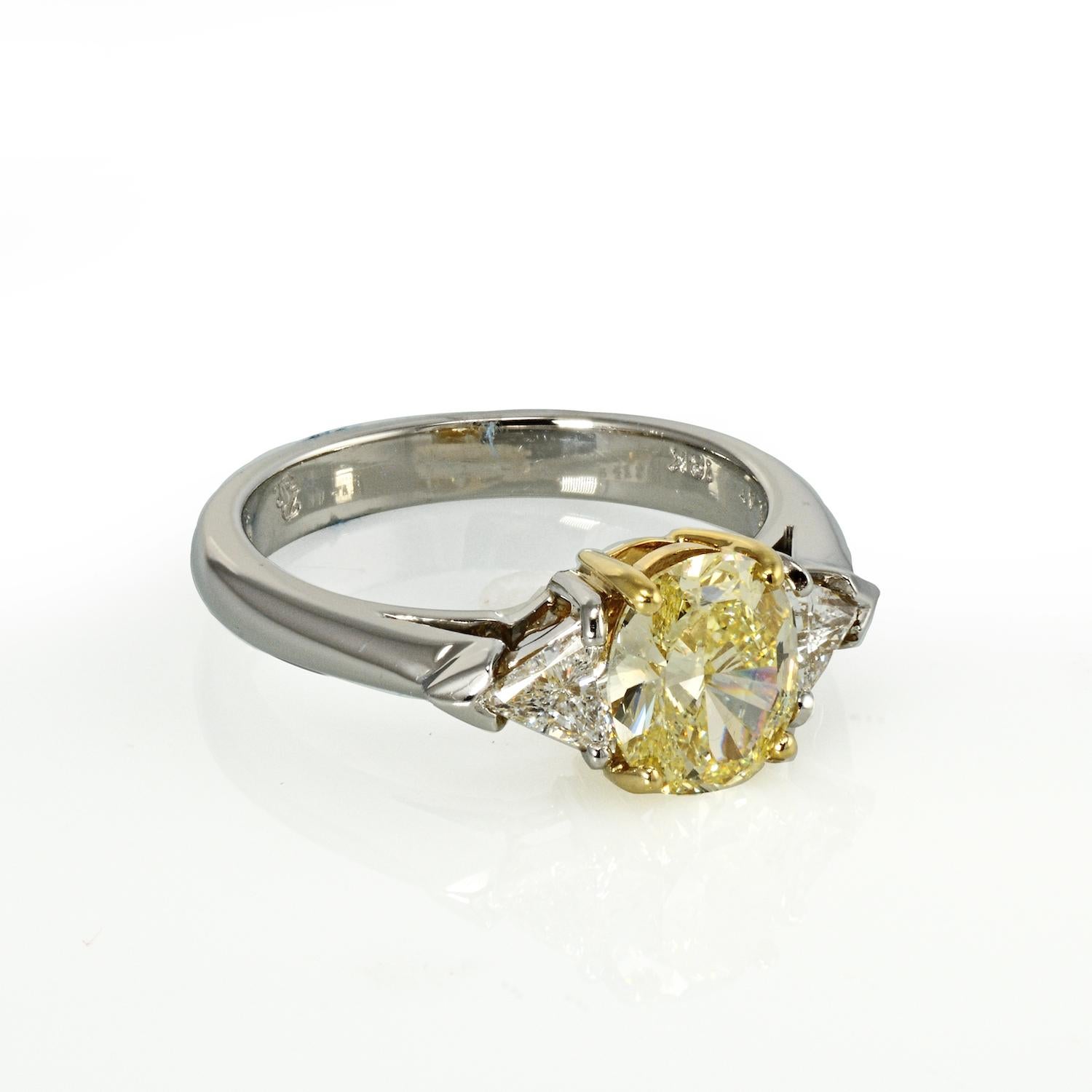 Ladies beautiful platinum and 18kt yellow gold three stone diamond ring featuring a 1.32 carat Oval-cut Fancy Yellow diamond. Two trilliant-cut diamonds are set on the shoulders totalling 0.37ct total weight of (VS) in clarity and (F-G) in color.